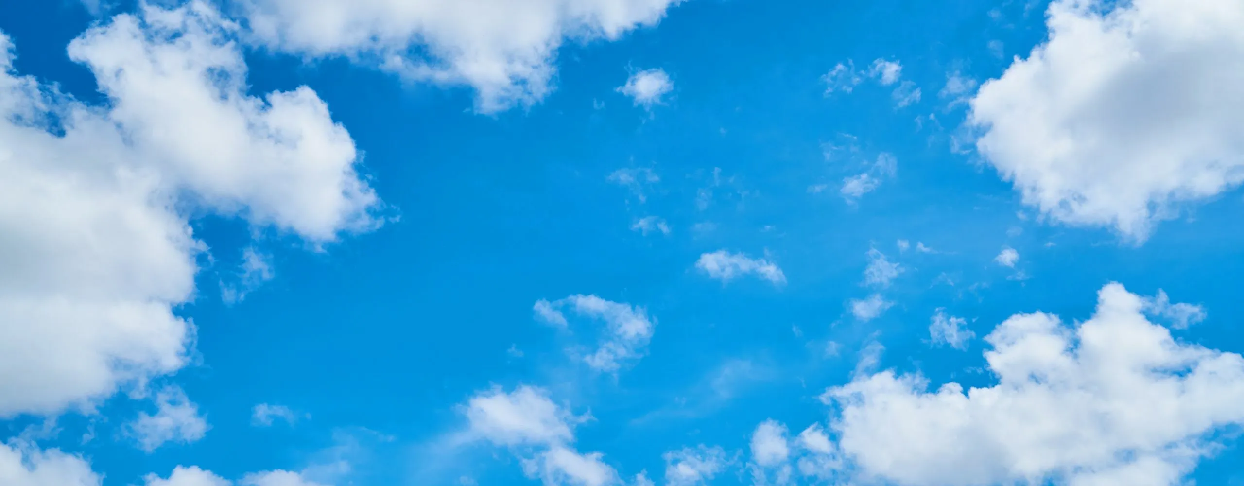 Vibrant blue sky with fluffy white clouds, offering a serene and clear atmosphere.