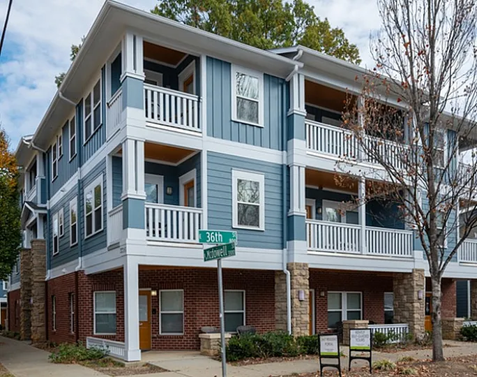 Charming three-story apartment building with balconies and brick facade, set on a street corner.