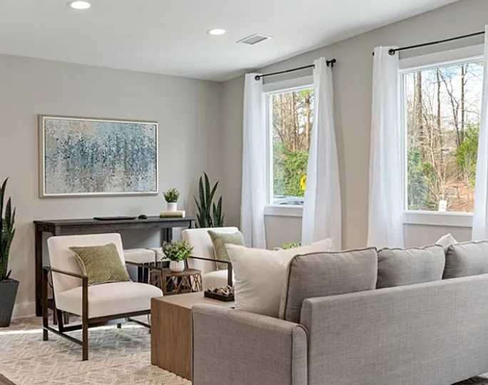 Bright and cozy living room with modern gray sofa, stylish decor, and large windows showcasing natural light.