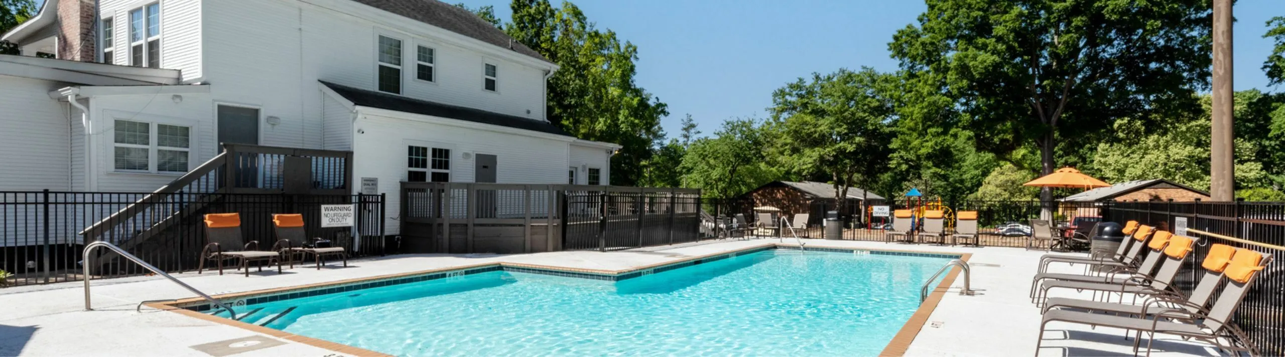 Inviting swimming pool with lounge chairs and scenic greenery backdrop.