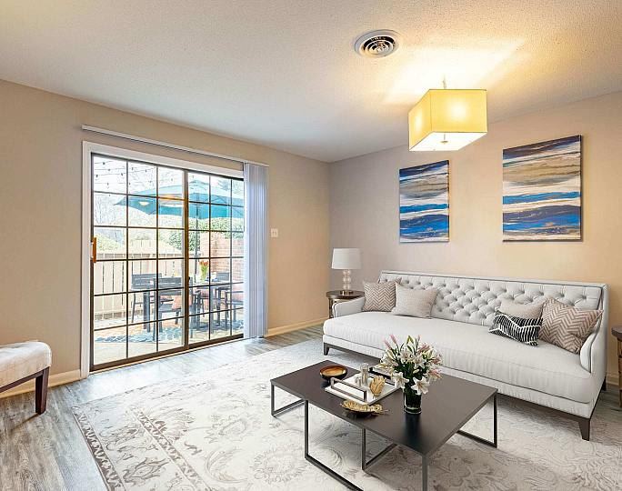 Inviting living room with cozy white sofa, elegant decor, and large glass doors leading to a charming outdoor patio.