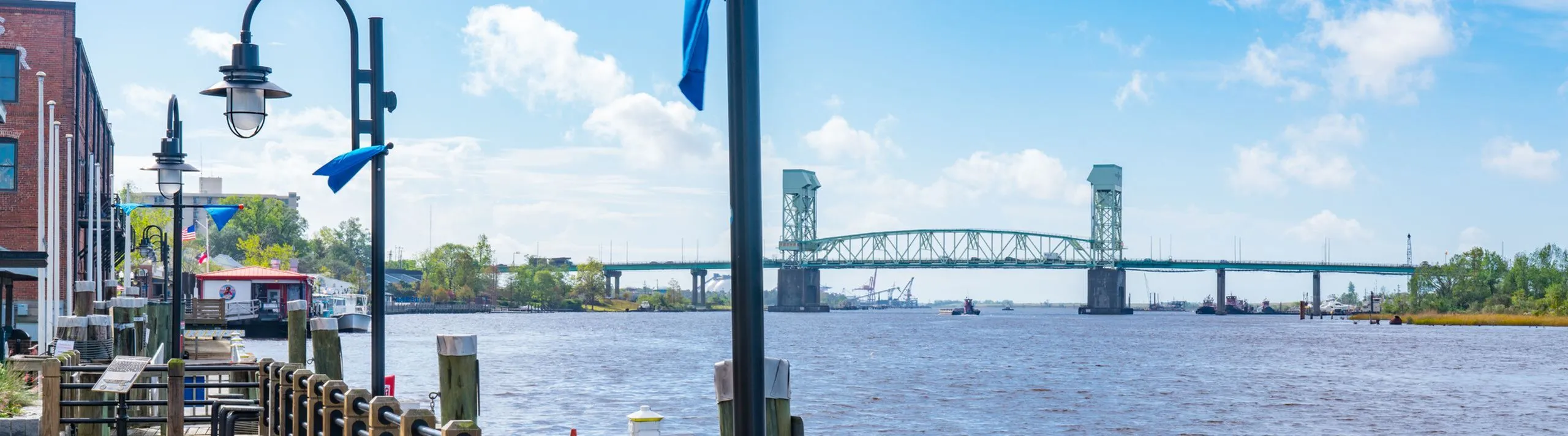 Scenic waterfront view featuring a charming dockside, vibrant greenery, and a striking blue sky, perfect for relaxing and sightseeing.