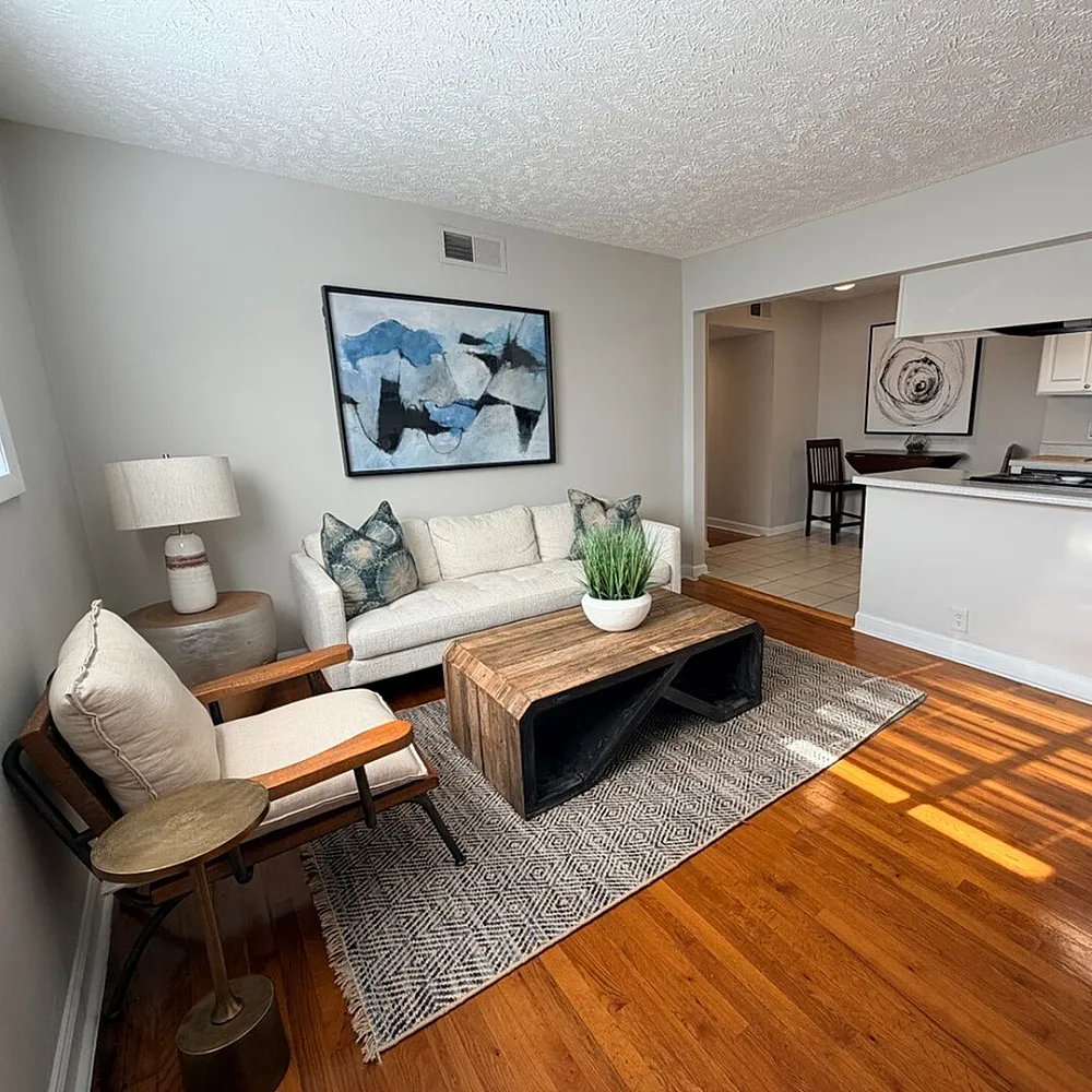 Inviting living space with modern decor, featuring a cozy sofa, stylish wooden table, and an open kitchen layout.