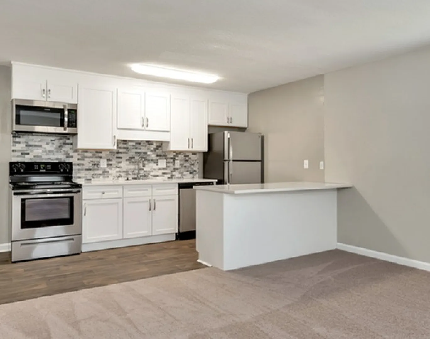 Modern open-plan kitchen and living area with sleek stainless steel appliances, stylish backsplash, and elegant flooring.