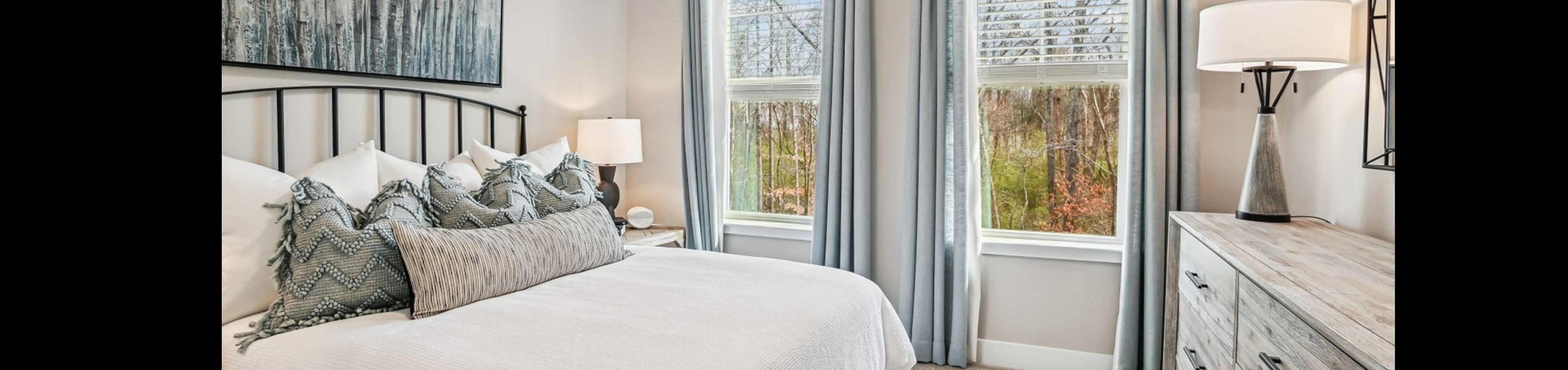 Bright and cozy bedroom with stylish decor featuring a scenic view, modern artwork, and elegant gray drapery.