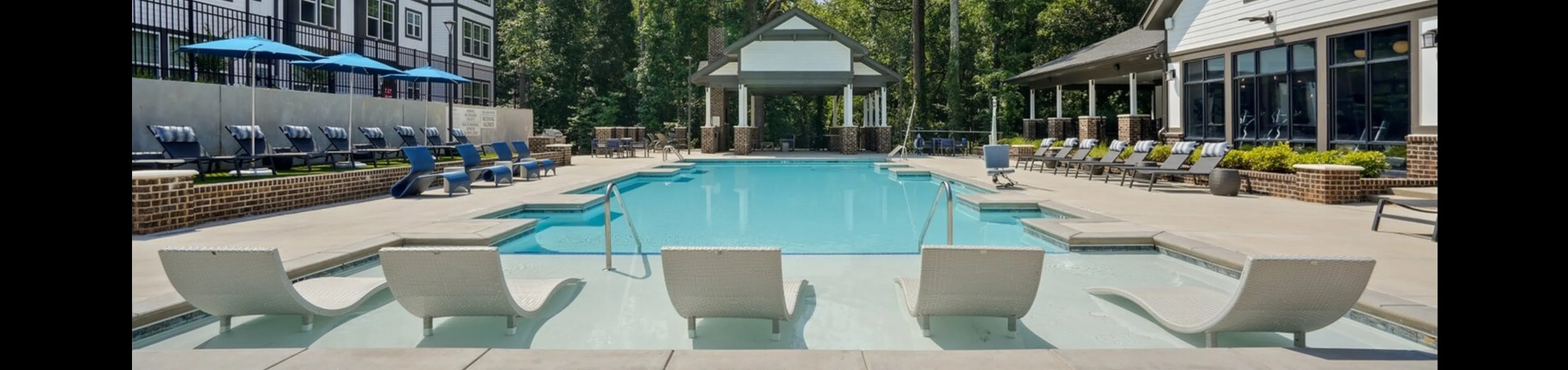 Luxurious apartment complex featuring a pristine resort-style swimming pool with stylish lounge chairs and modern architecture.