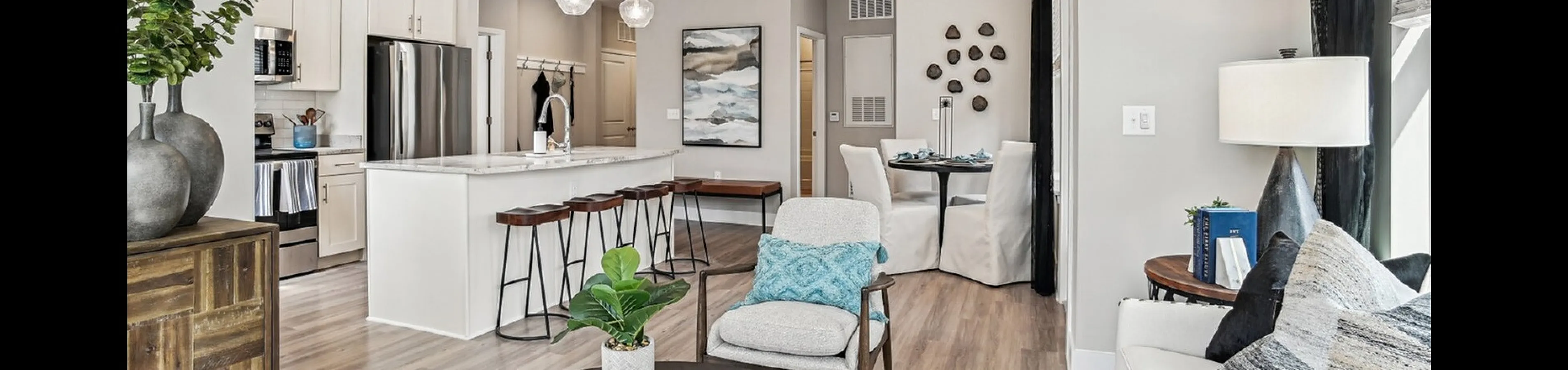 Chic modern living room with open-concept kitchen featuring white cabinetry, stylish bar stools, and elegant pendant lighting.