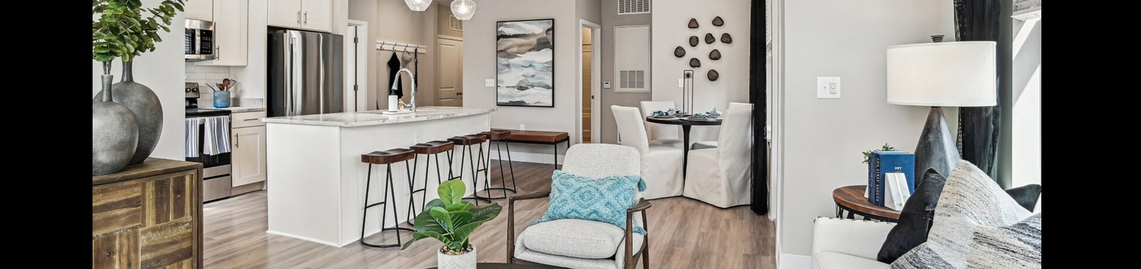 Chic modern living room with open-concept kitchen featuring white cabinetry, stylish bar stools, and elegant pendant lighting.