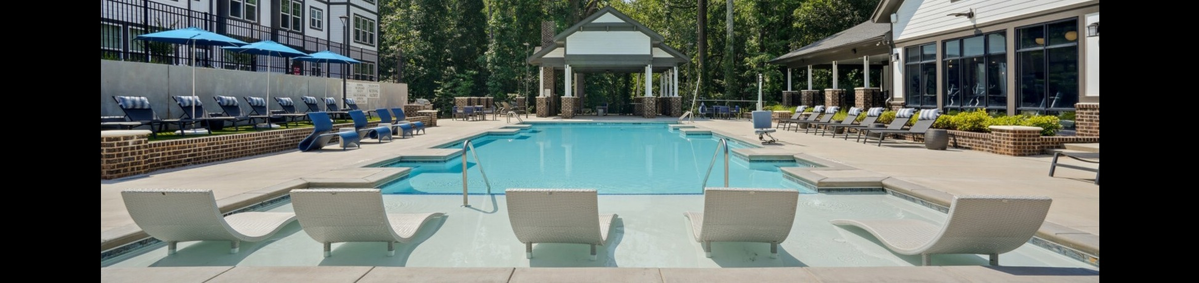Luxurious apartment complex featuring a pristine resort-style swimming pool with stylish lounge chairs and modern architecture.