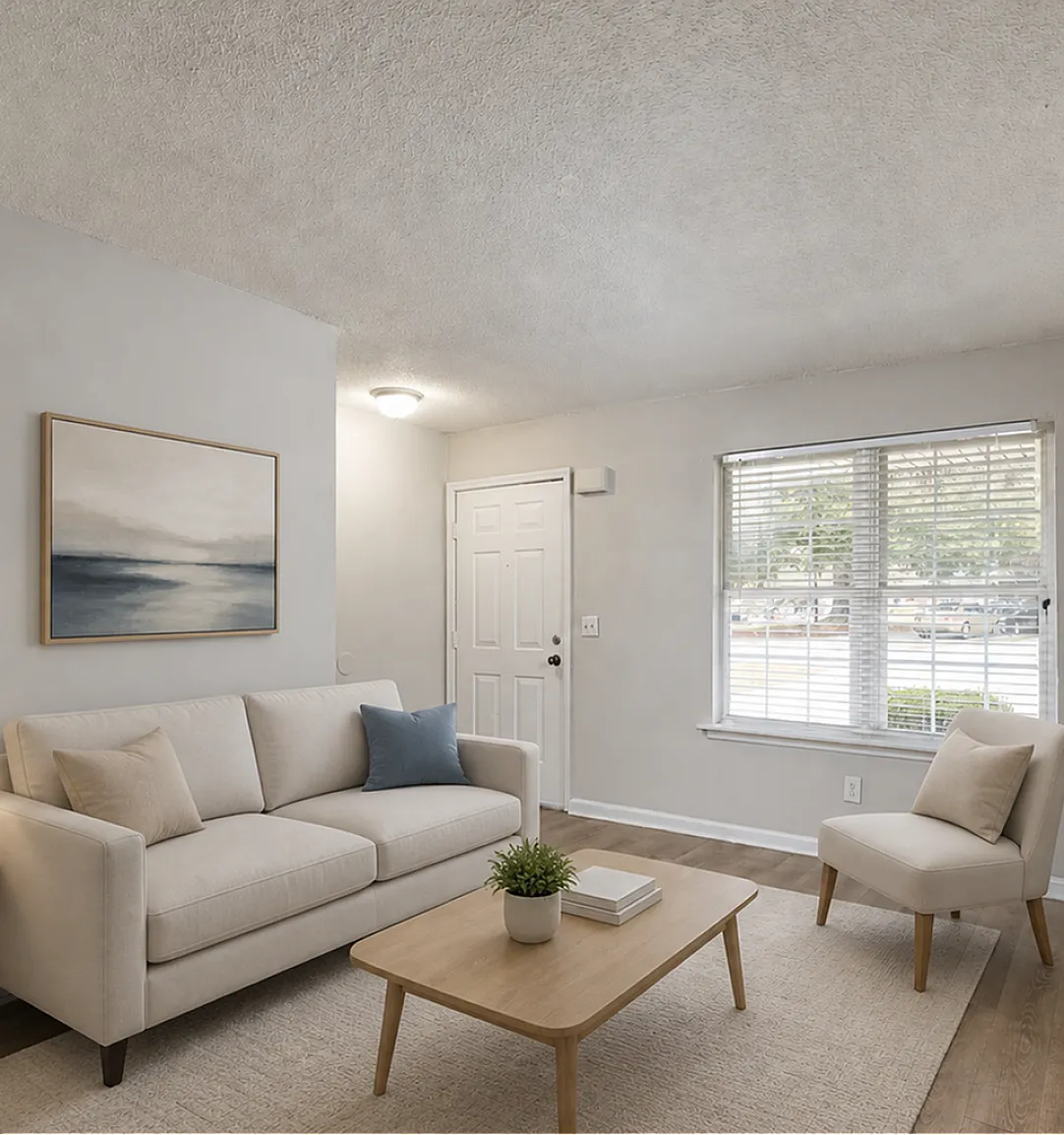 Bright and inviting living room with stylish beige sofa and pastel cushions, complemented by a modern coffee table and lush greenery near a large window.