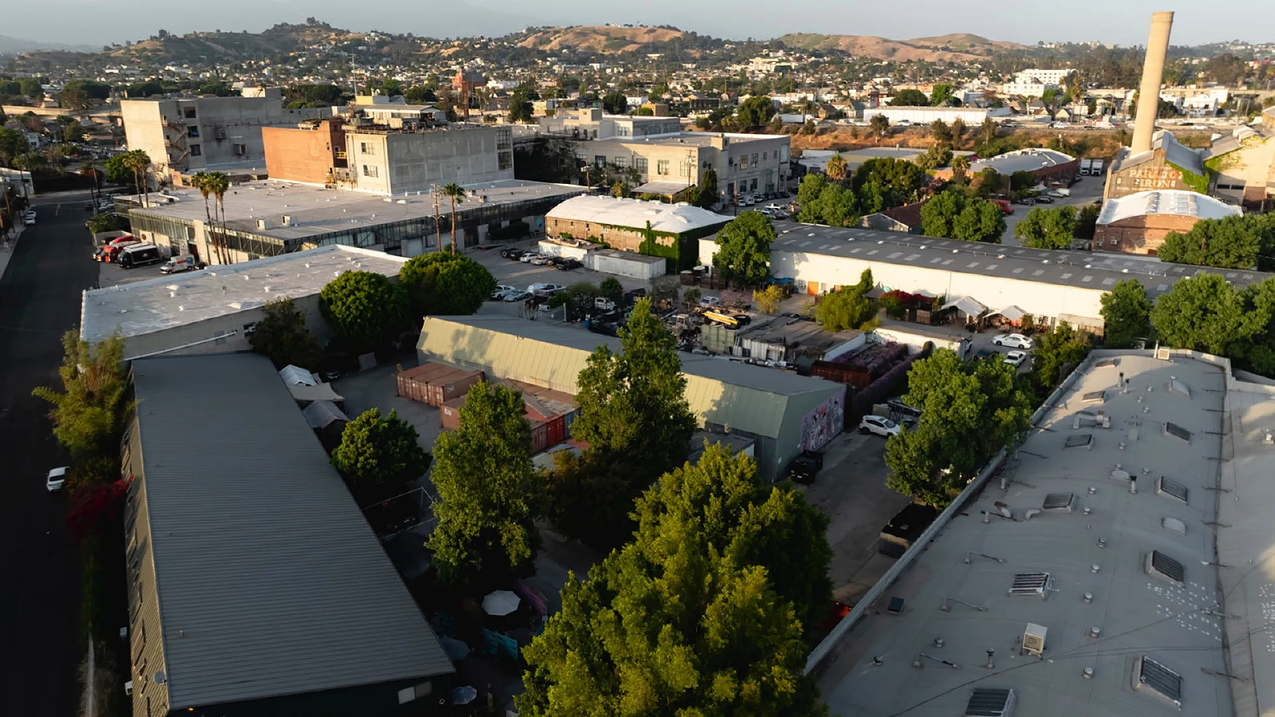 Charming urban scene showcasing a vibrant industrial area surrounded by lush greenery and hills in the background.