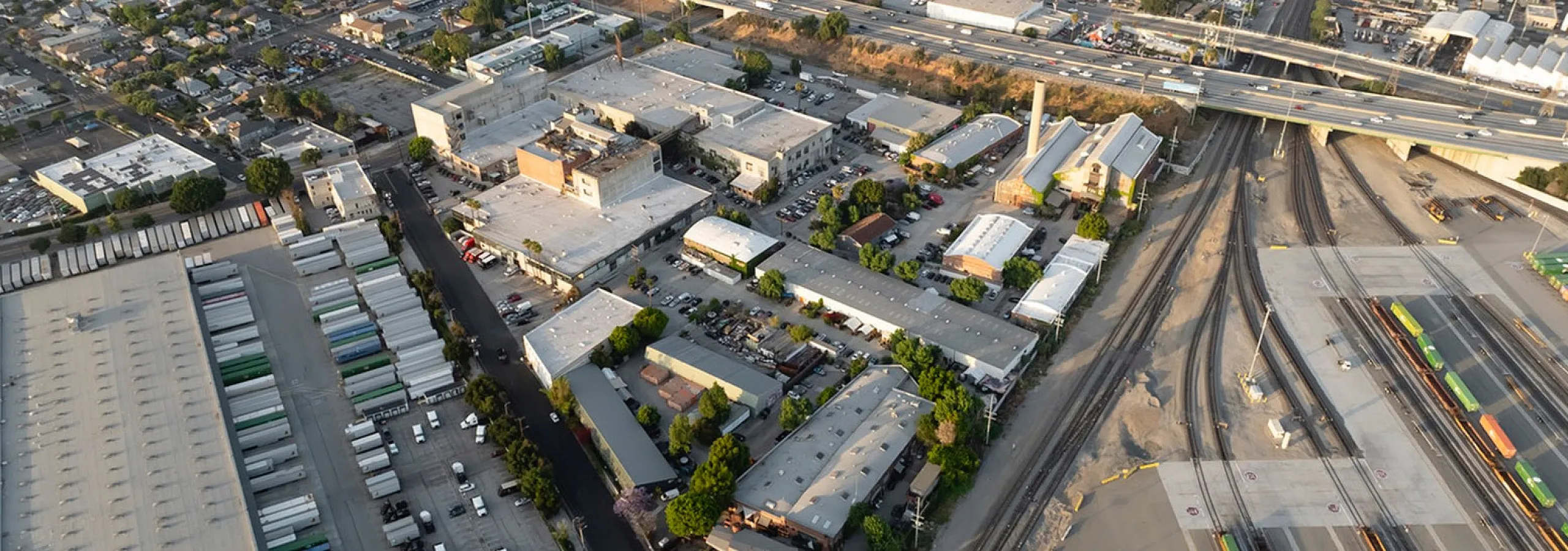 Vibrant aerial view of an industrial area with warehouses, train tracks, and a bustling network of roads, showcasing a dynamic logistics hub.