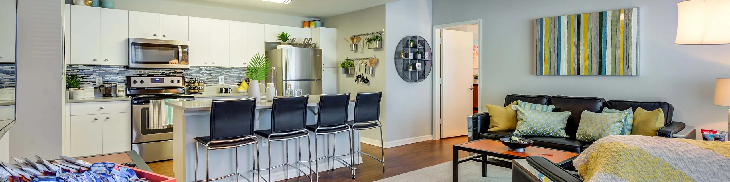 Modern open-plan living area featuring a stylish kitchen with stainless steel appliances, cozy seating with decorative cushions, and chic interior design elements.