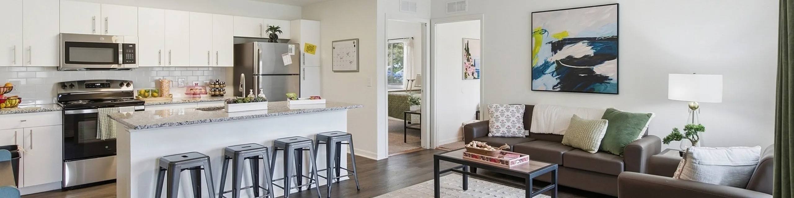 Open-concept living space with modern kitchen, sleek countertops, and cozy seating area in a bright, welcoming apartment.