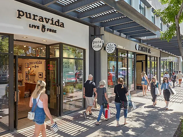 Vibrant shopping center with dynamic storefronts and lively foot traffic, featuring modern architecture and lush greenery.