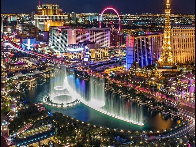 Vibrant cityscape of Las Vegas at night, showcasing dazzling lights, iconic architecture, and a captivating water fountain display.