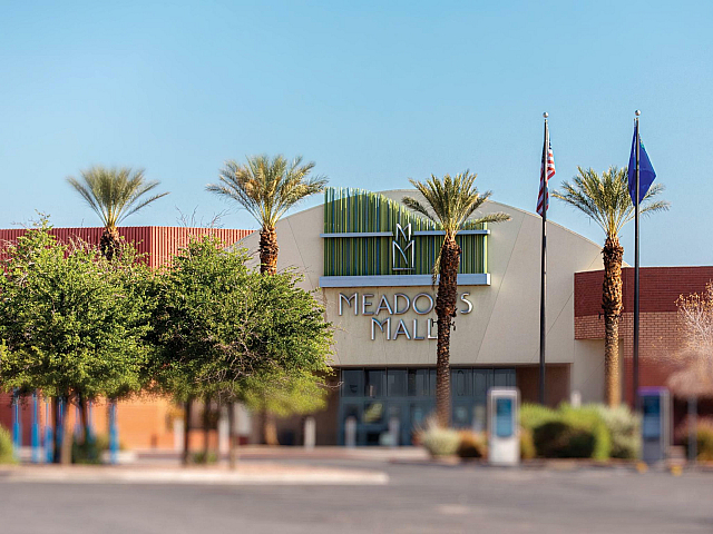 Vibrant exterior view of Meadows Mall surrounded by palm trees and clear blue skies.
