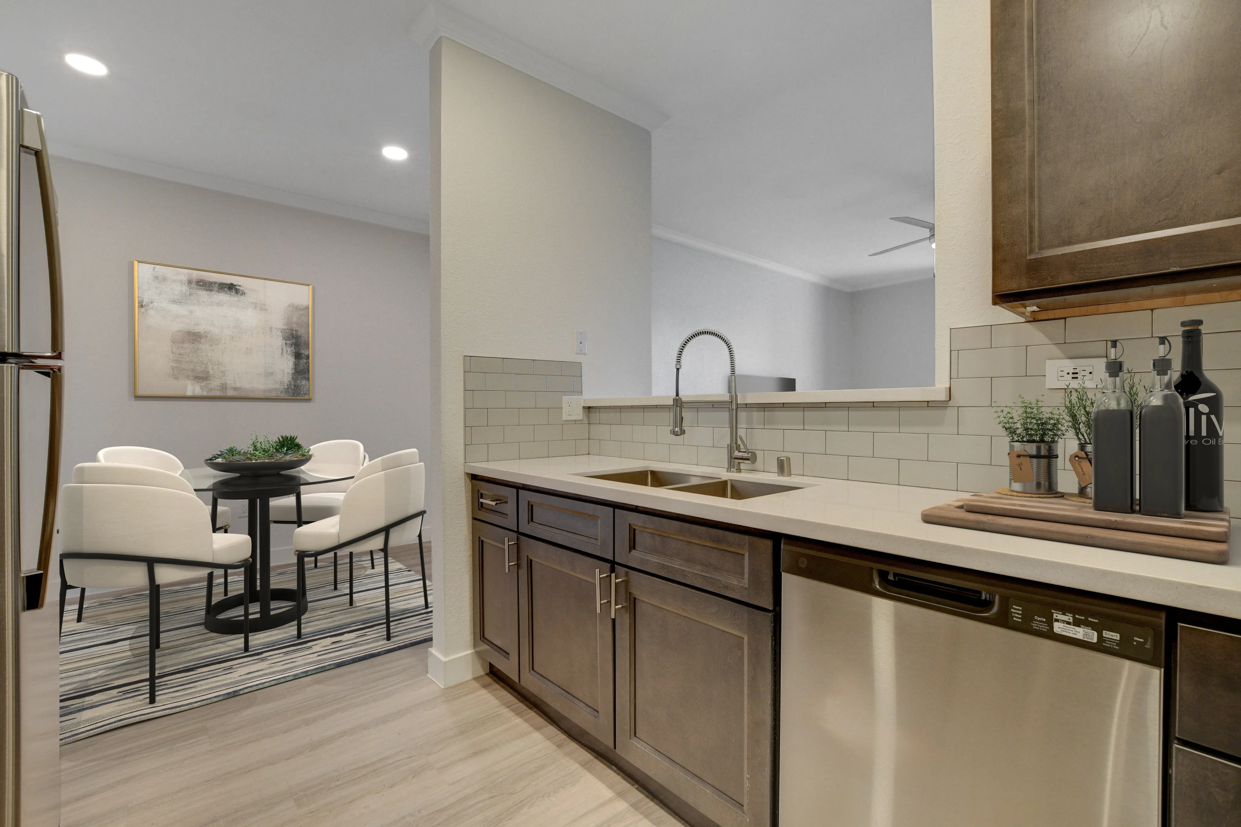 Modern open-plan kitchen with sleek cabinetry, a double sink, and dining area featuring elegant seating and artistic decor.