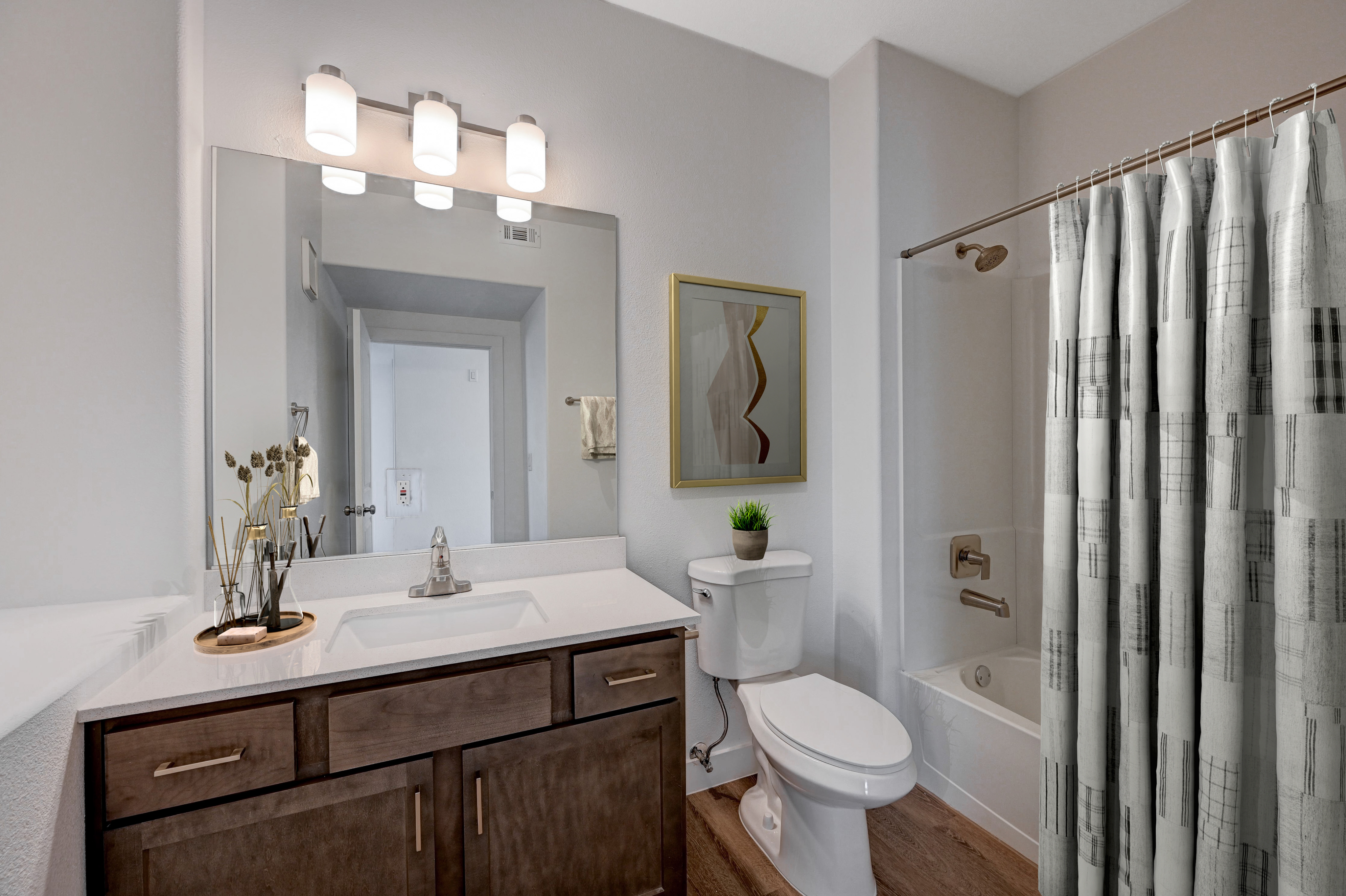 Modern bathroom with sleek vanity, elegant lighting, and a stylish shower curtain, exuding a luxurious ambiance.