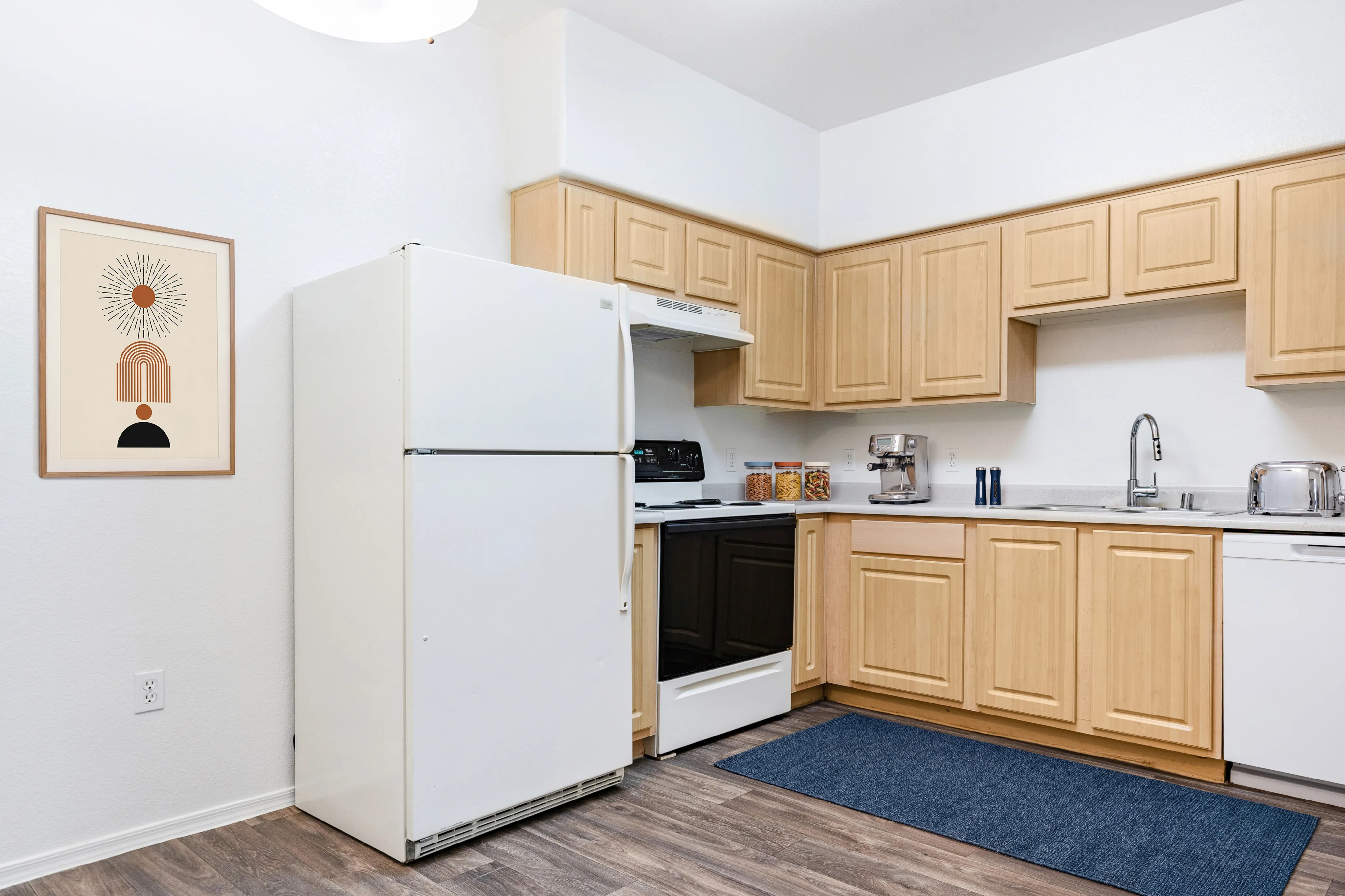 Charming kitchen with light wood cabinets, modern appliances, and stylish artwork, perfect for culinary creativity.