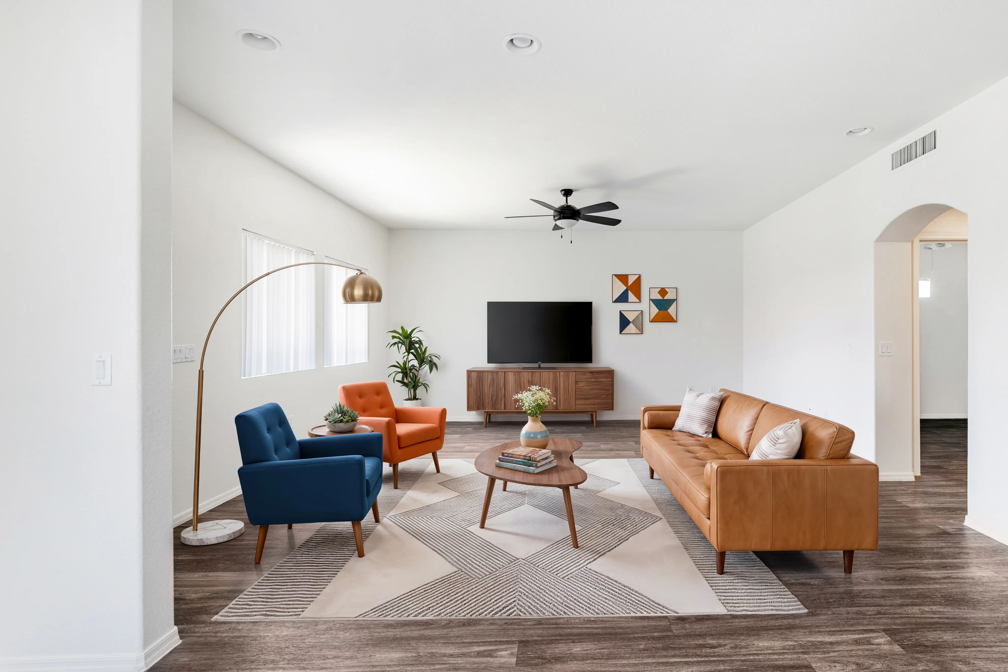 Chic contemporary living room with sleek leather sofa, vibrant accent chairs, modern decor, and stylish wood flooring.