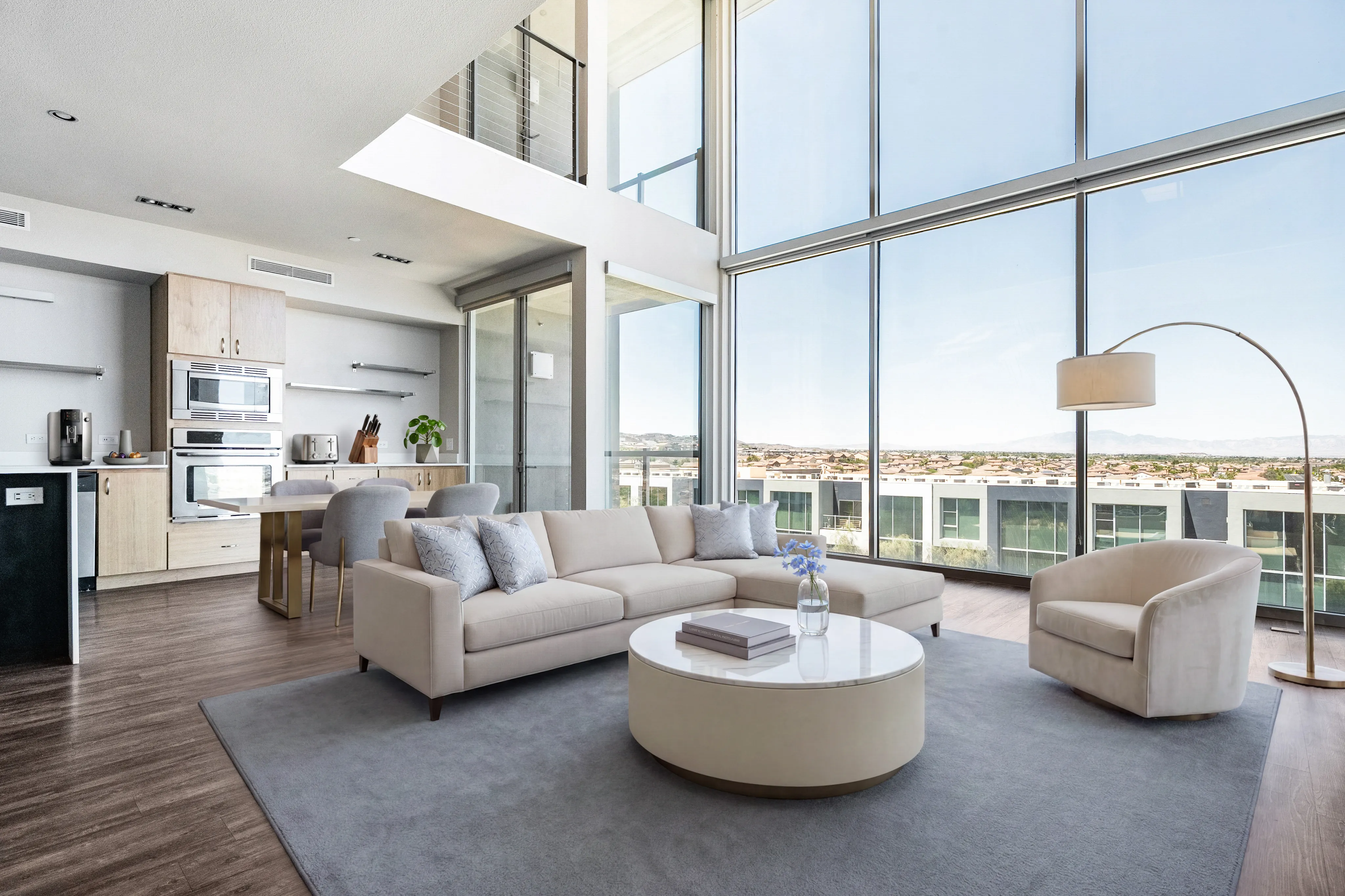 Modern apartment interior featuring a spacious living area with floor-to-ceiling windows, stylish sofa, and an elegant arc lamp. Open-concept kitchen with state-of-the-art appliances and chic dining set.