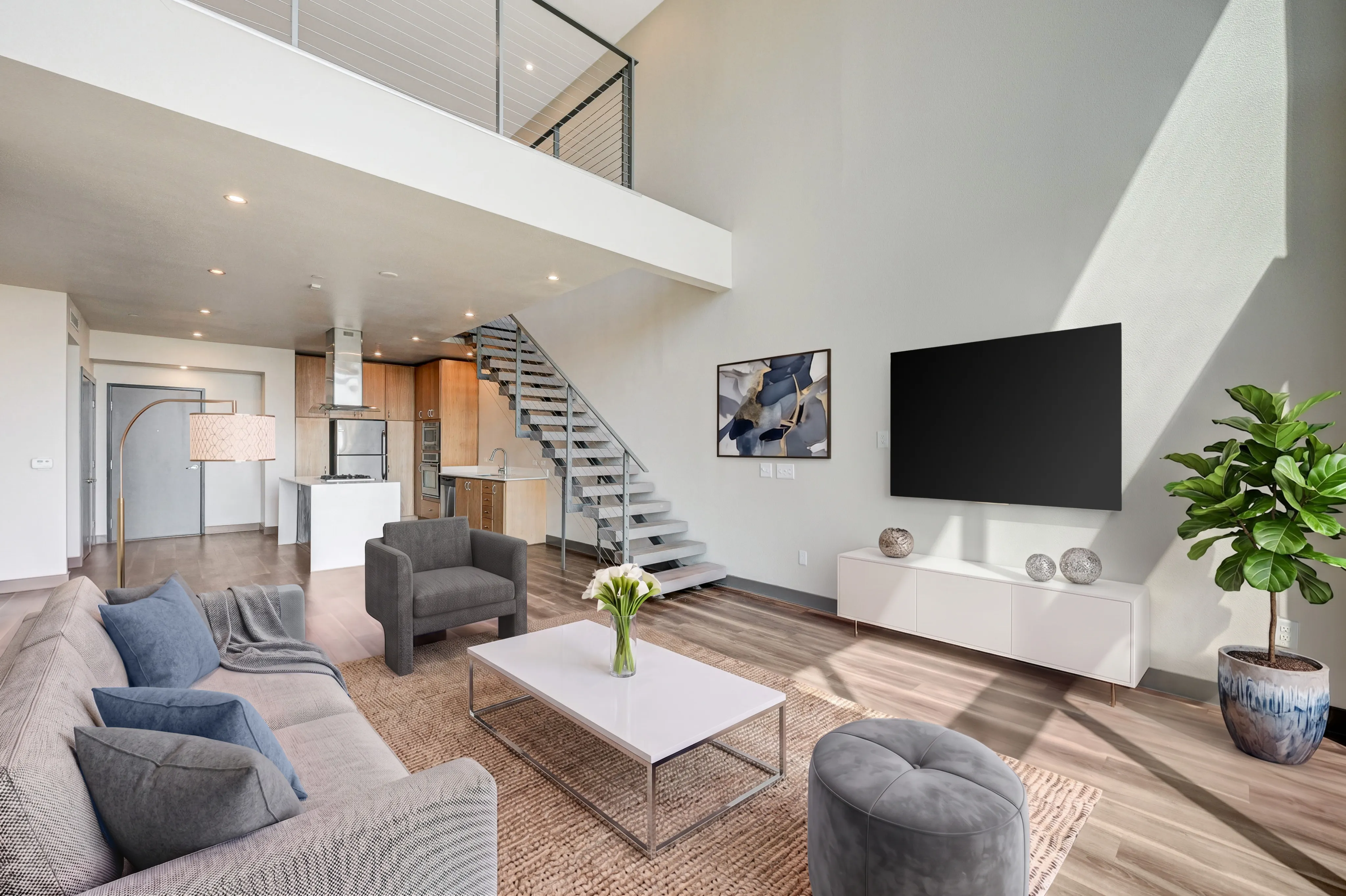 Modern and spacious living area with loft, contemporary furniture, sleek staircase, and abundant natural light.