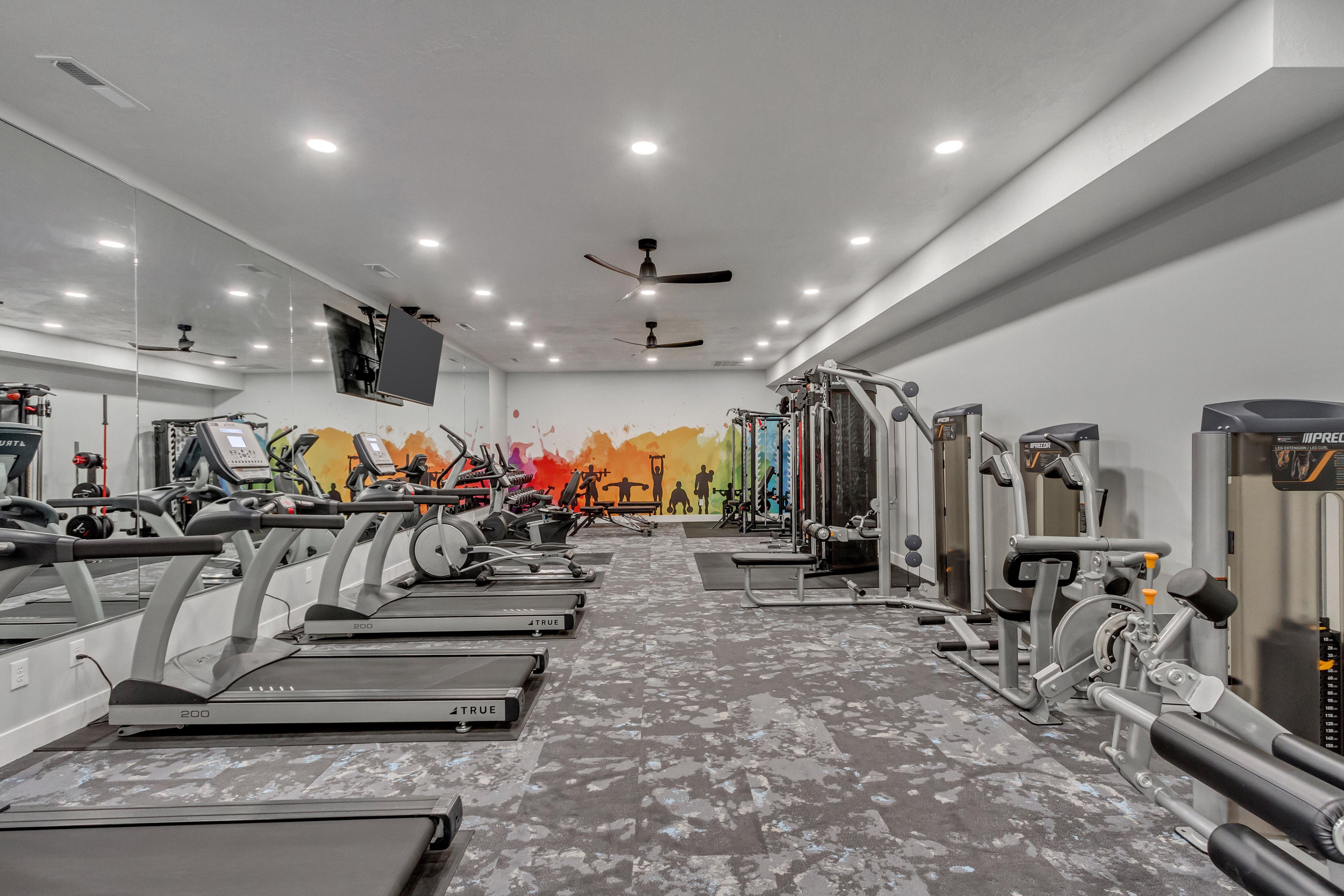 Modern fitness center with state-of-the-art equipment, vibrant mural, and mirrored walls for an energetic workout experience.