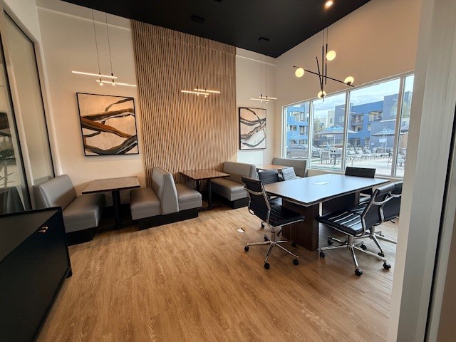 Modern office space with sleek wooden flooring, stylish lighting, and a large window view, ideal for productive meetings.