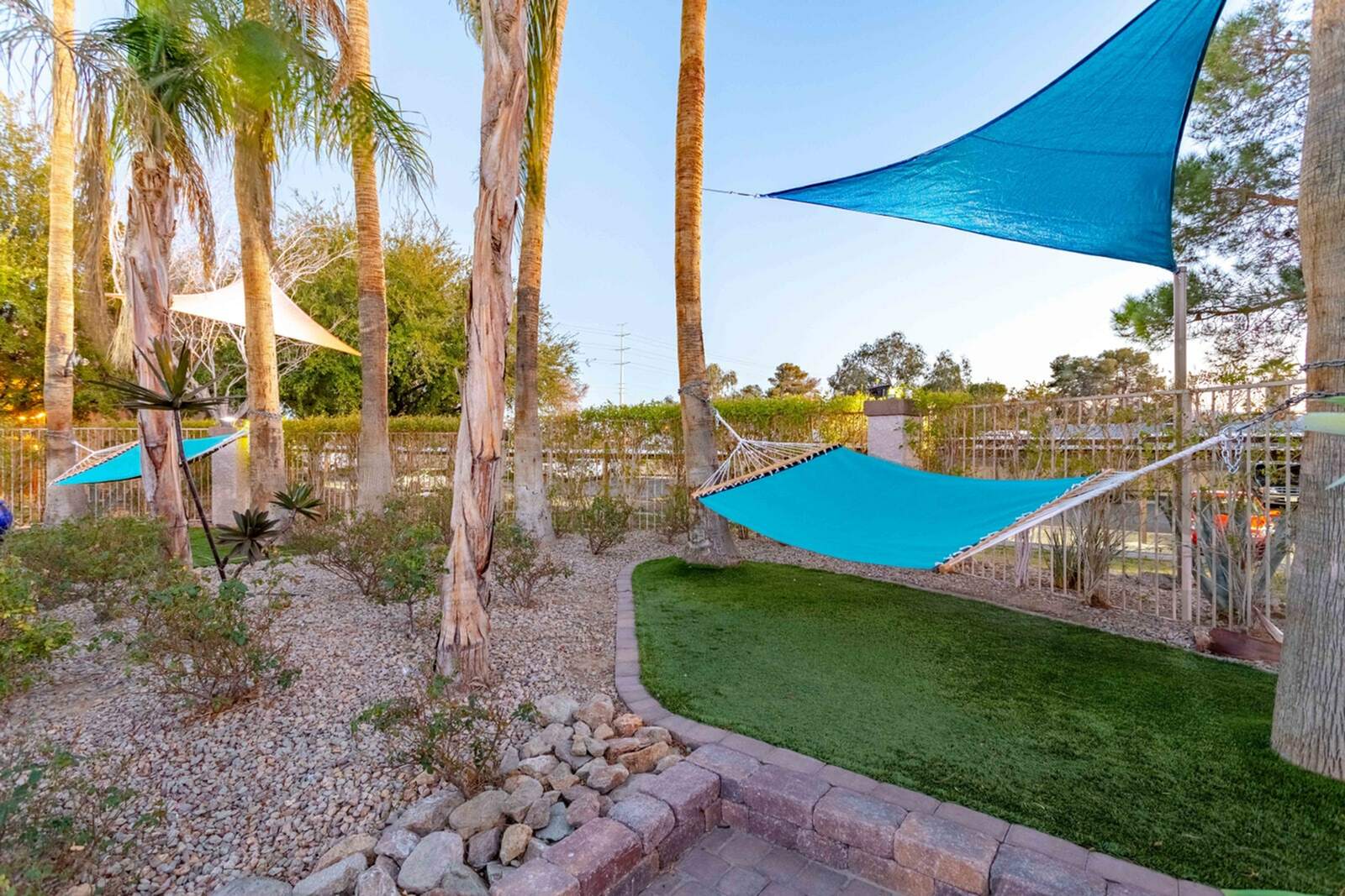 Tranquil outdoor oasis with hammocks under shaded trees, perfect for relaxation and enjoying nature.