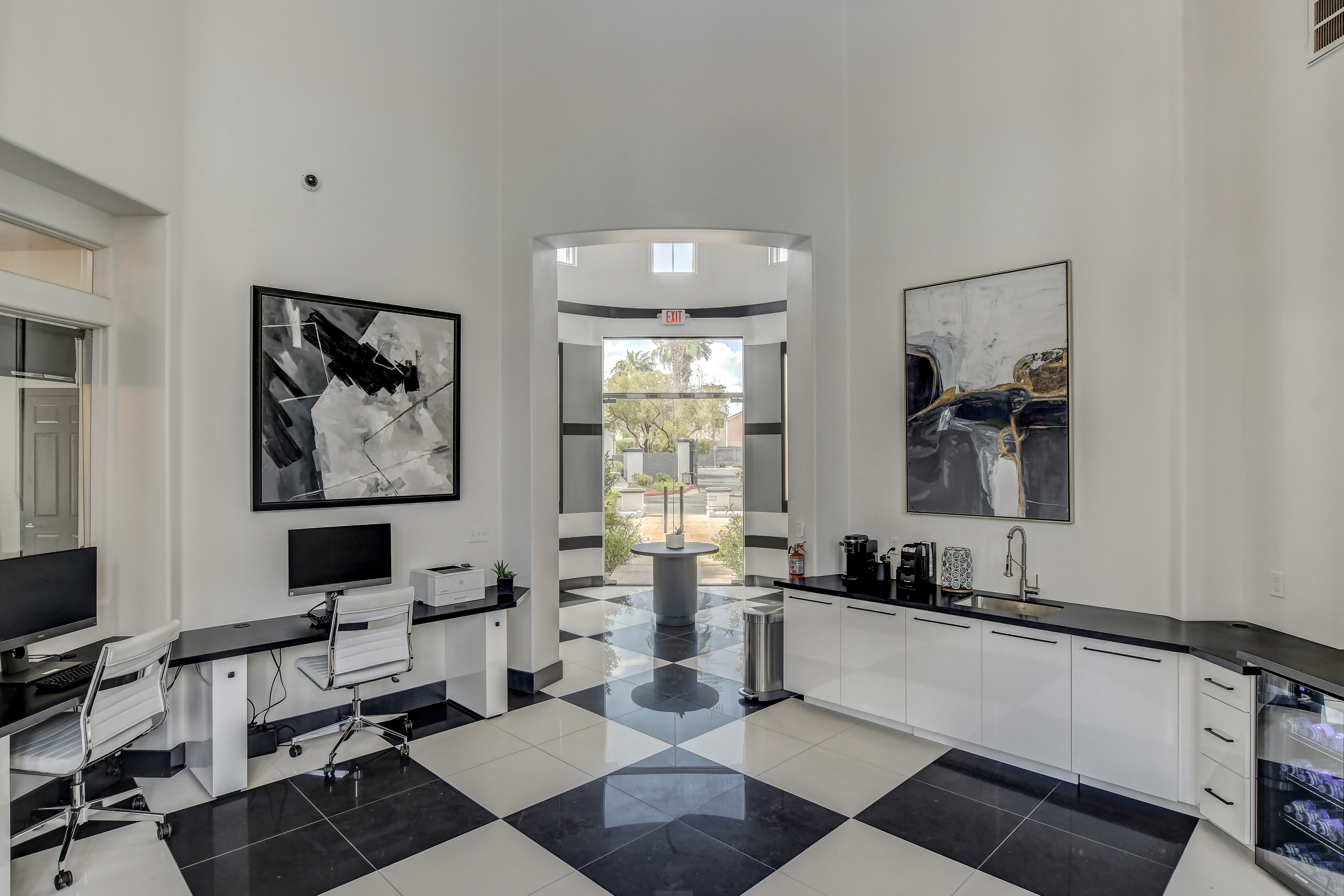 Elegant office space featuring modern design with sleek black and white decor, artistic wall art, and large windows for natural light.