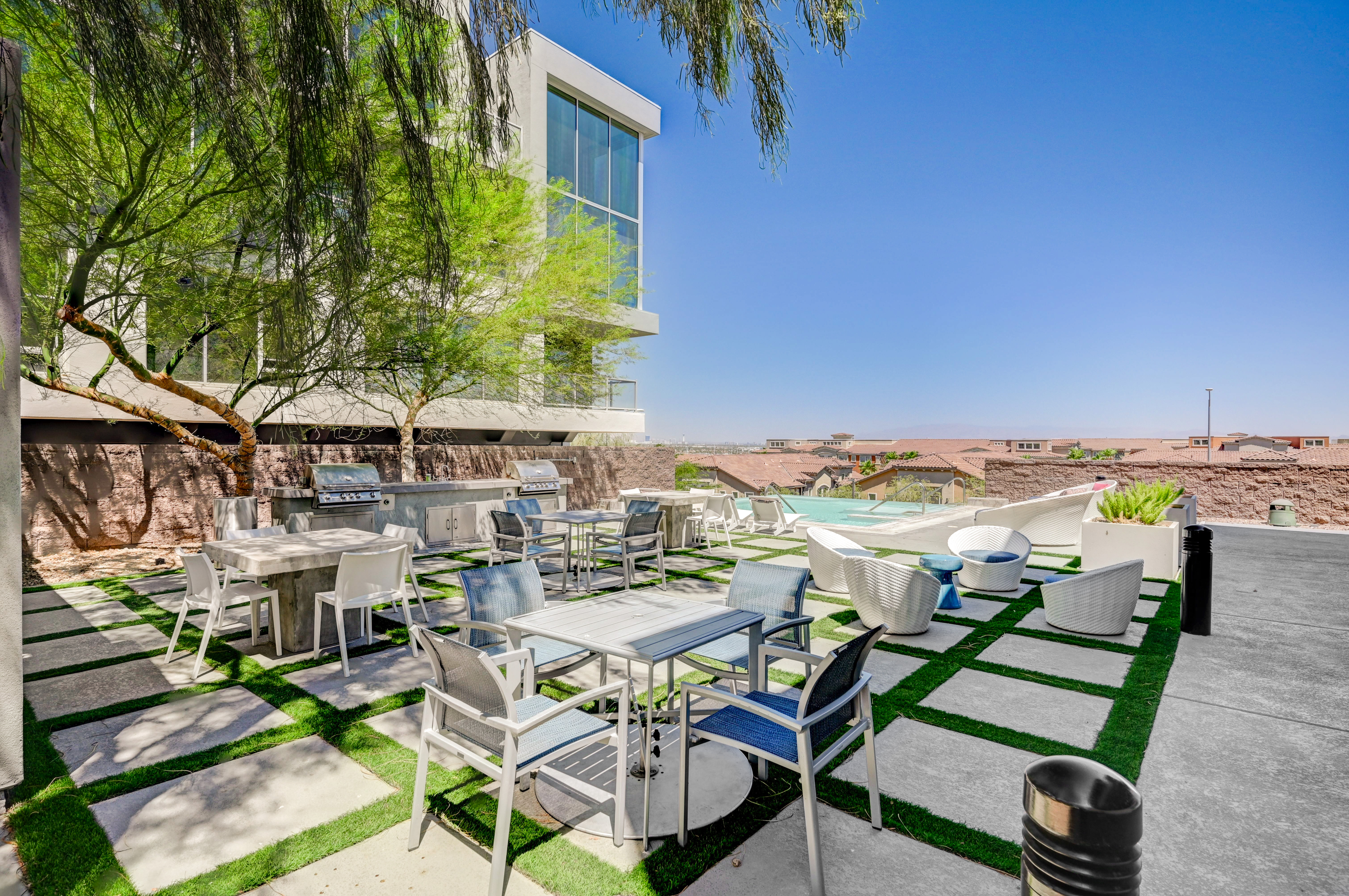 Elegant rooftop patio with stylish seating, dining area, and modern grills, offering breathtaking city skyline views.