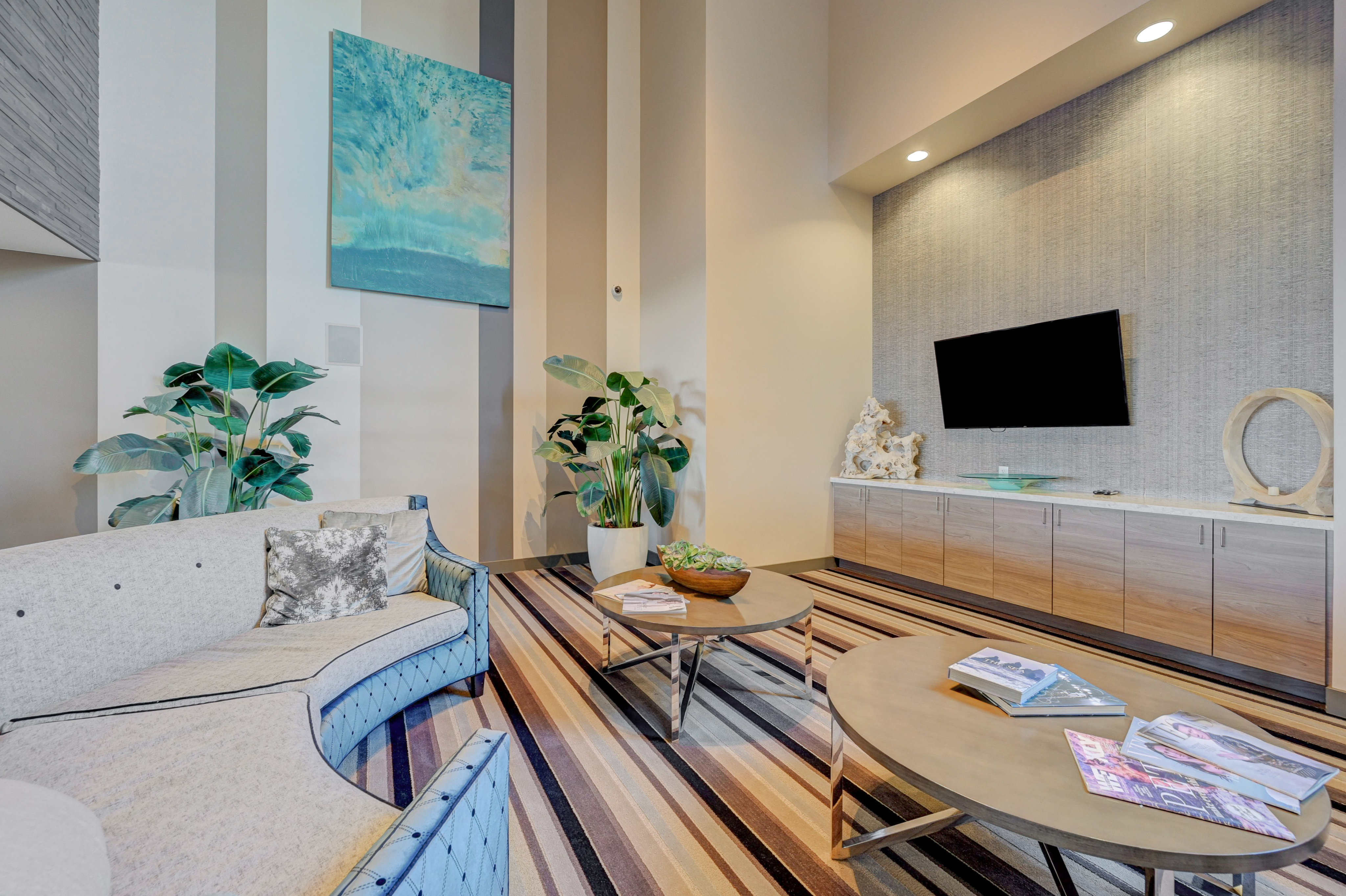 Elegant living room with sleek modern decor, featuring a plush sectional sofa, vibrant artwork, and stylish indoor plants.
