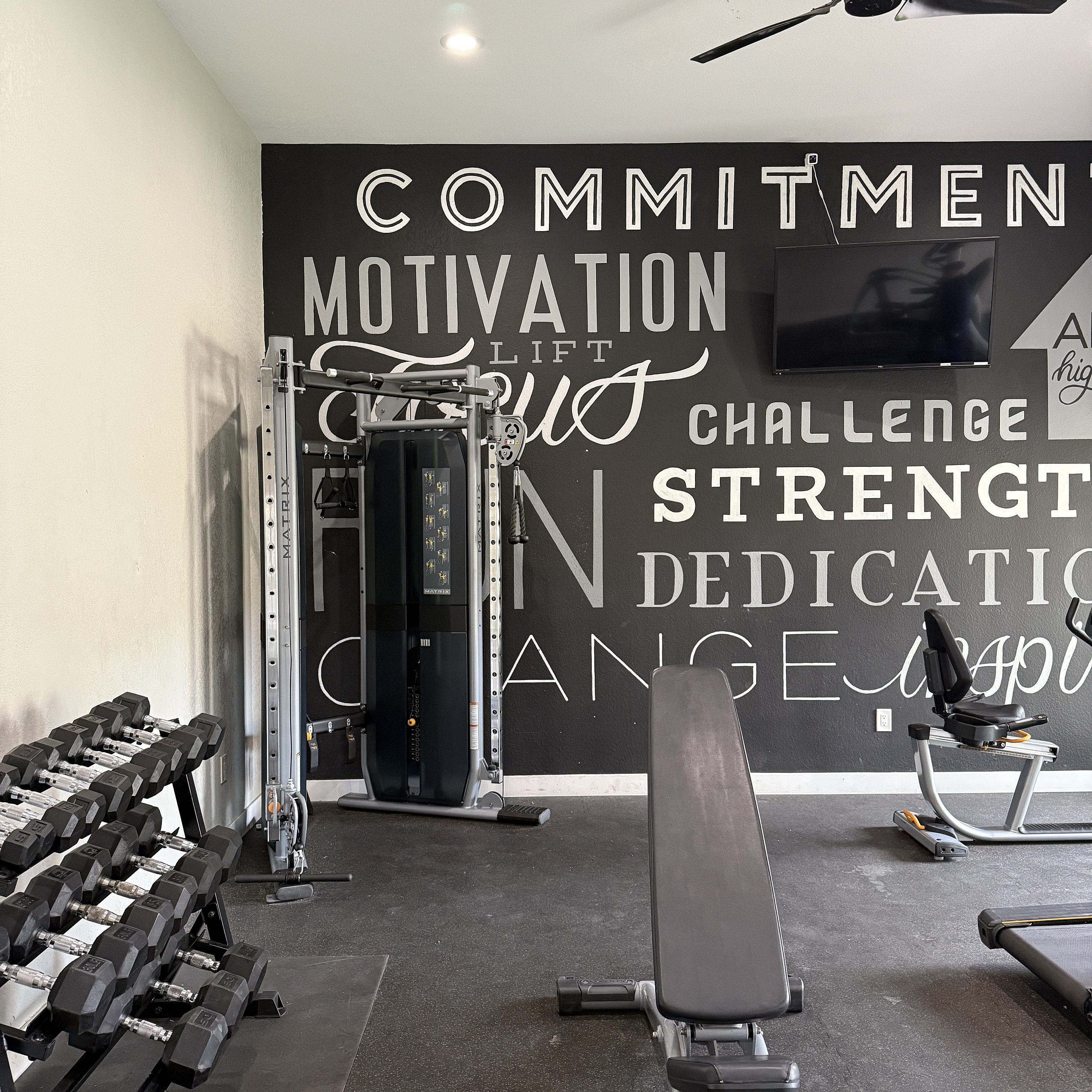Modern fitness room with motivational wall art, gym equipment, and a sleek bench for a complete workout experience.