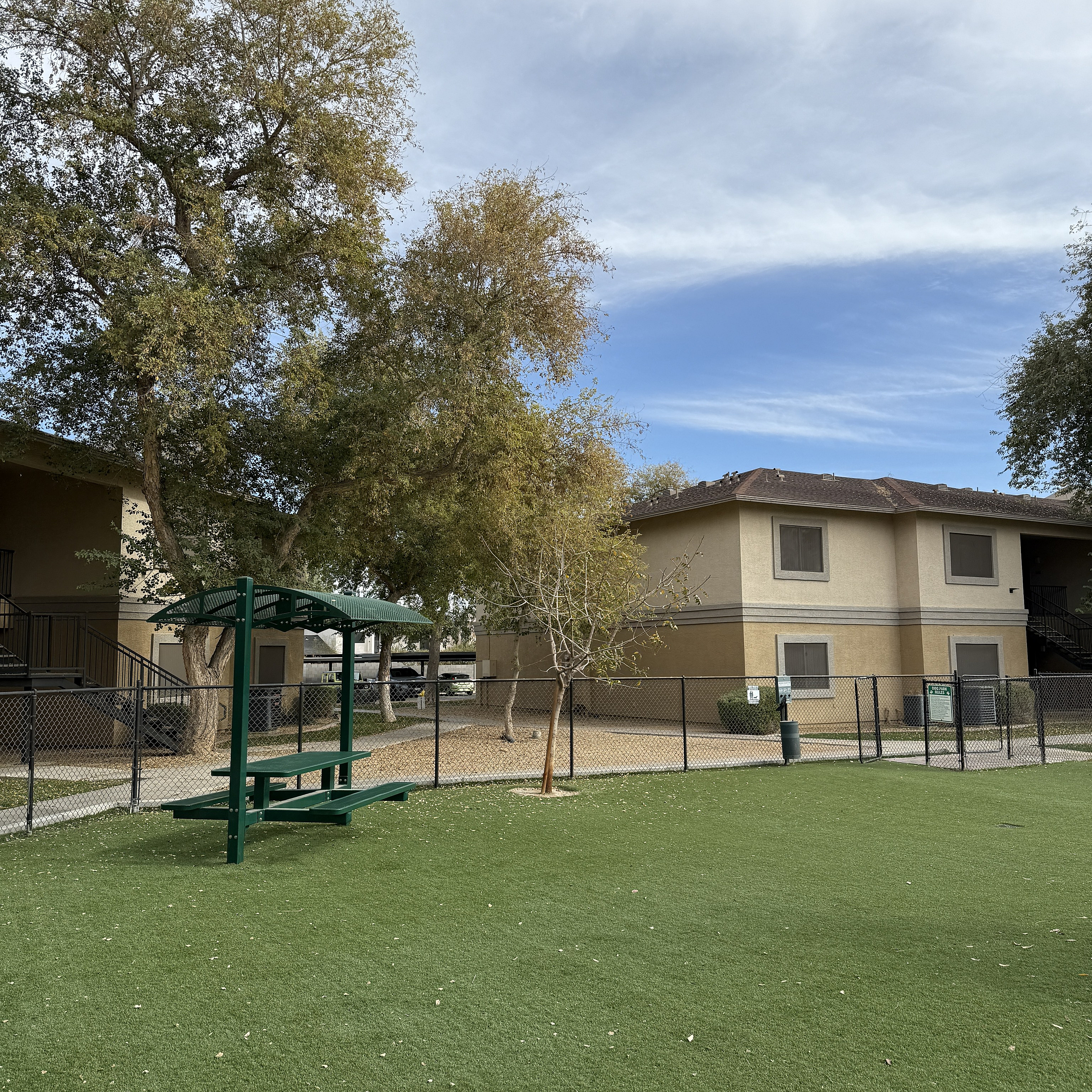 Charming apartment exterior featuring lush trees and a vast green lawn, ideal for outdoor relaxation.