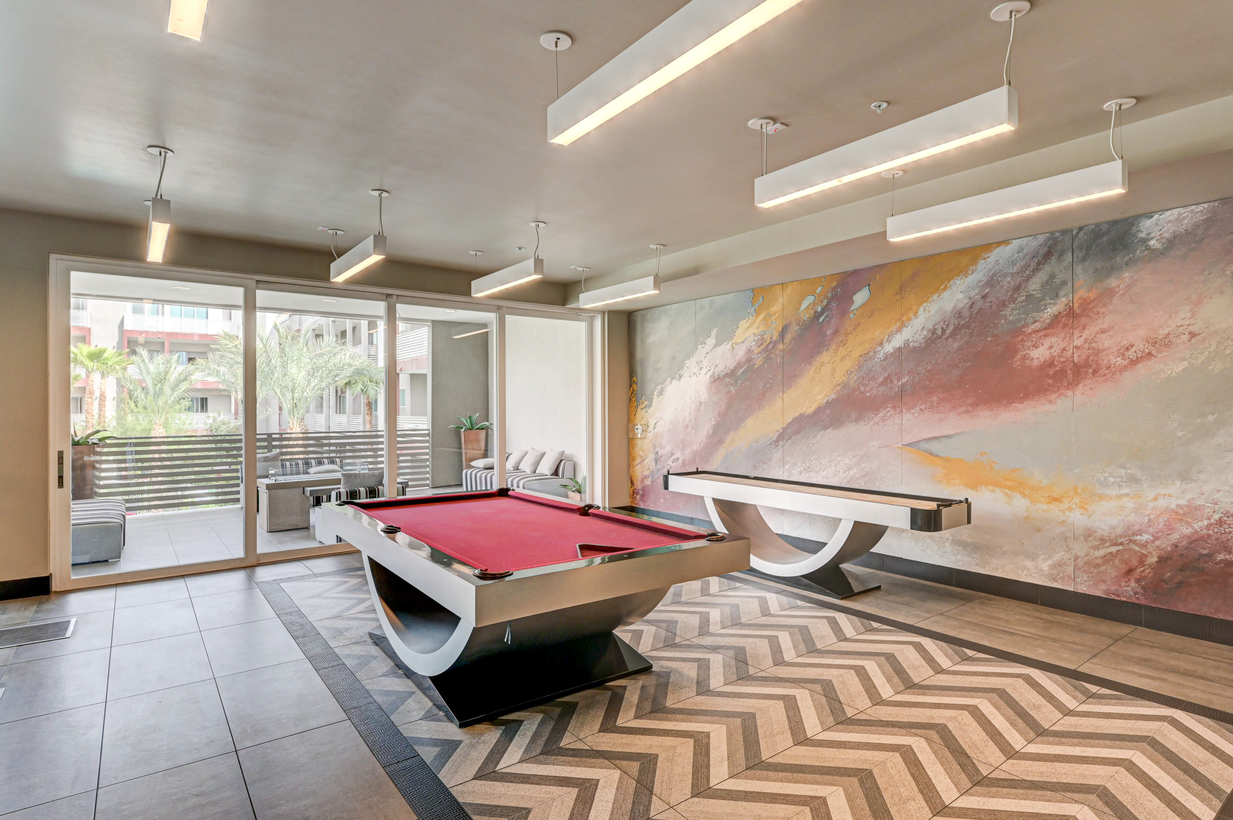 Contemporary recreation room featuring a sleek pool table, vibrant abstract wall art, and a cozy lounge area with outdoor views.