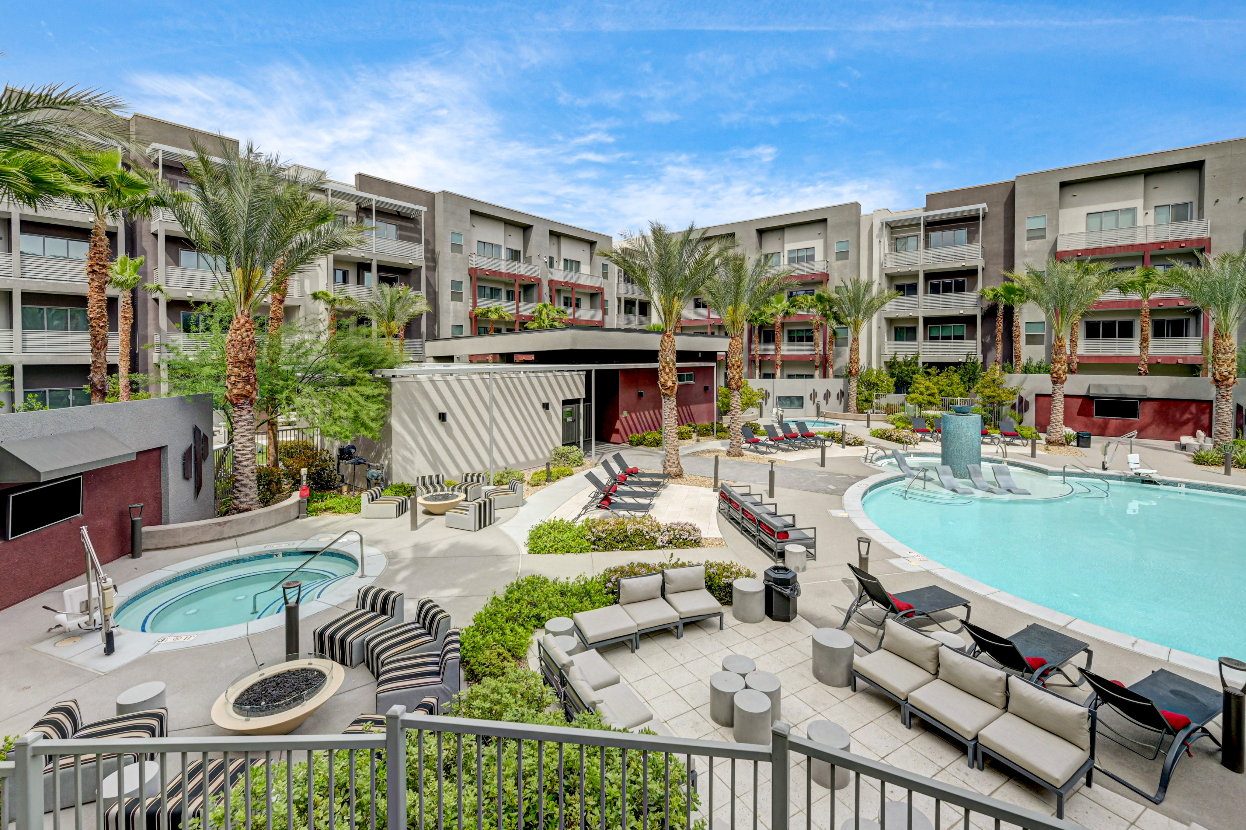 Luxurious apartment complex featuring a stunning outdoor pool, elegant palm landscaping, and modern lounging areas perfect for relaxation.
