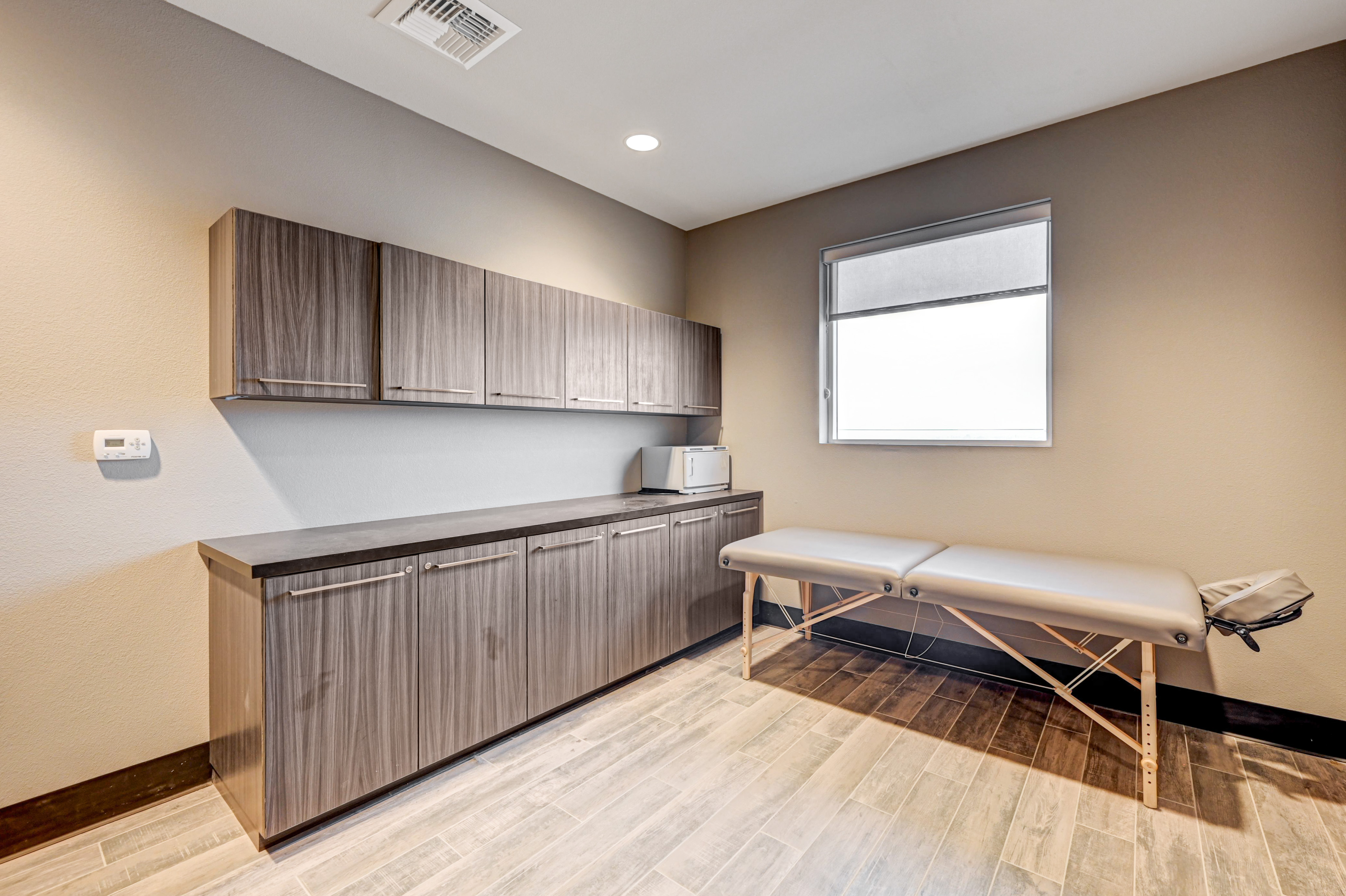 Modern therapy room with sleek cabinetry and a comfortable massage table, featuring warm lighting and a serene atmosphere.