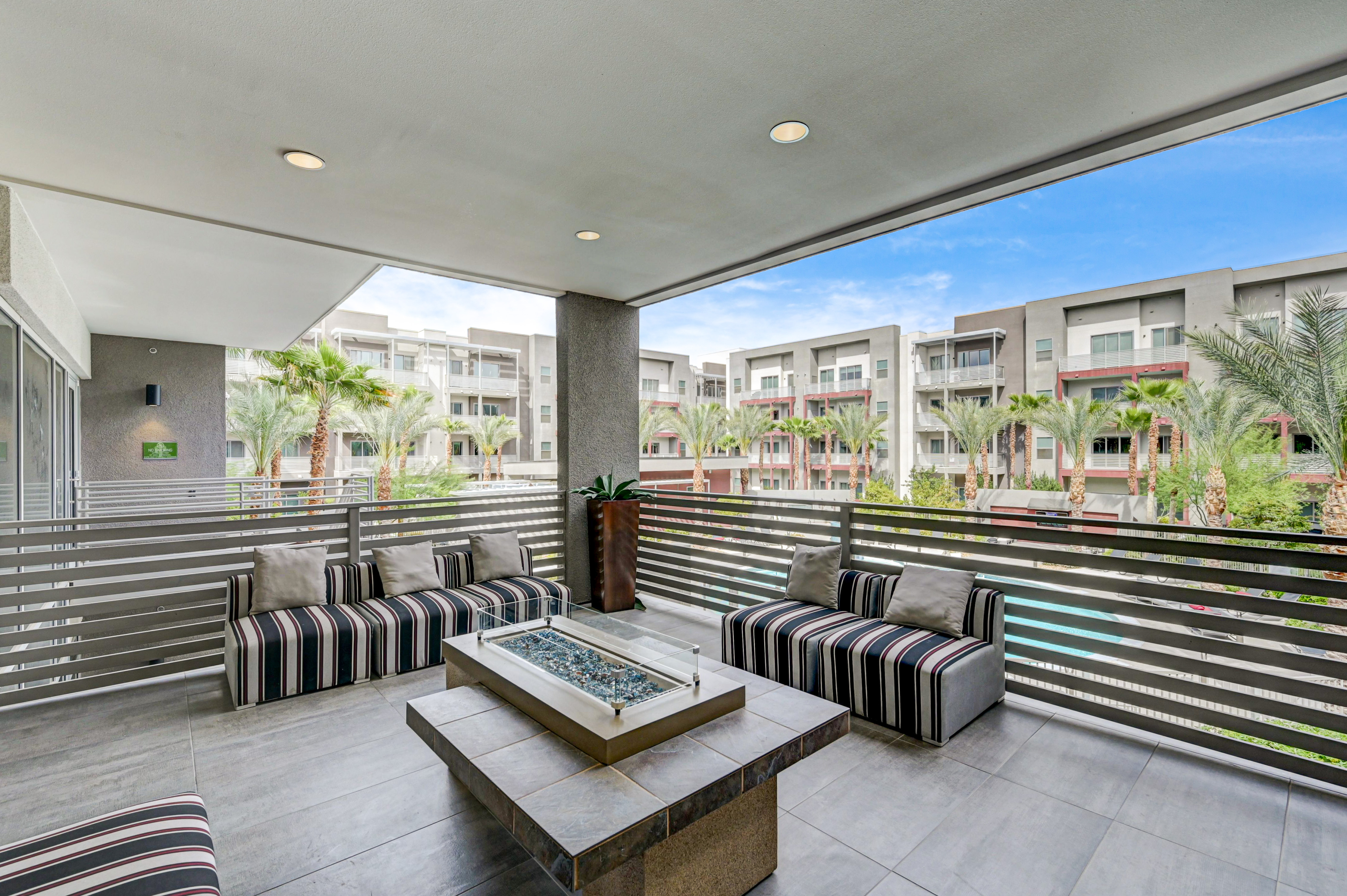 Contemporary apartment balcony with stylish seating and scenic views of palm trees and modern buildings.