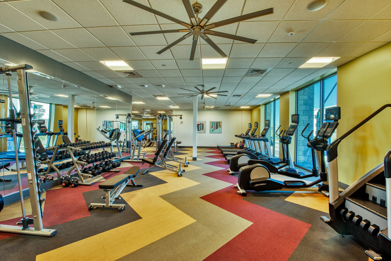 Vibrant fitness center featuring state-of-the-art equipment, spacious design, and large windows for natural light.