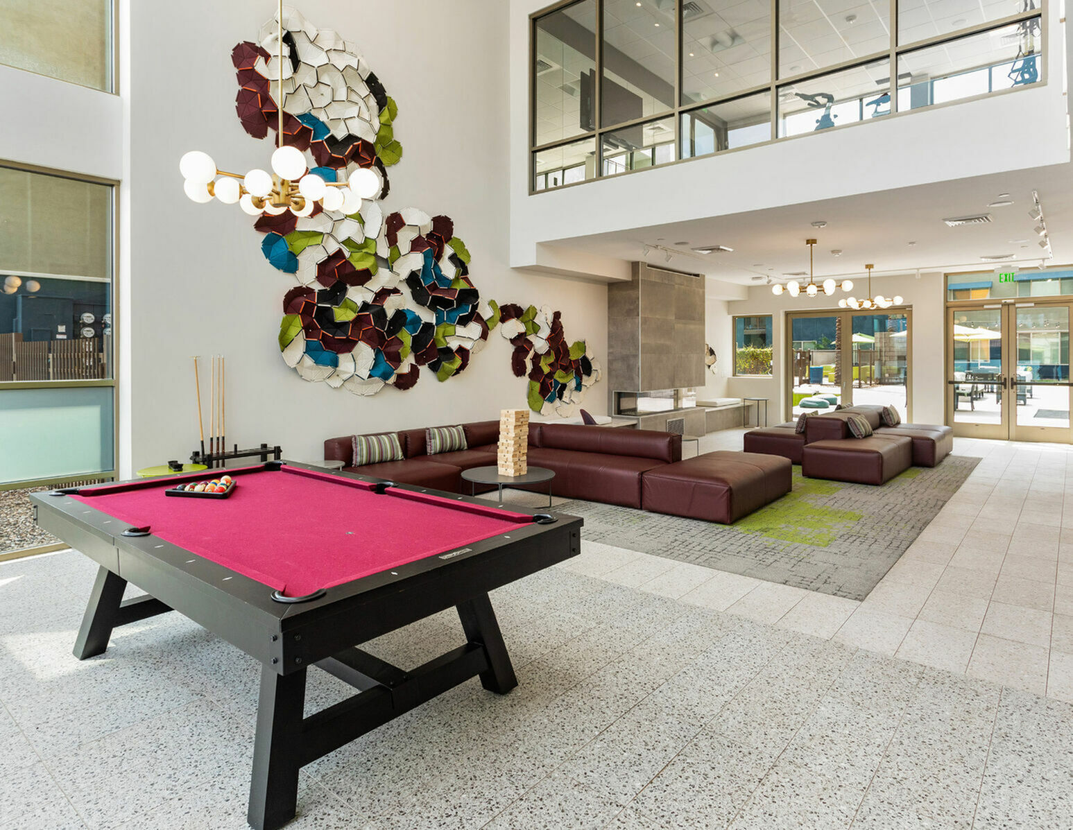 Contemporary lounge featuring a vibrant wall art installation, modern lighting, and a stylish billiard table.