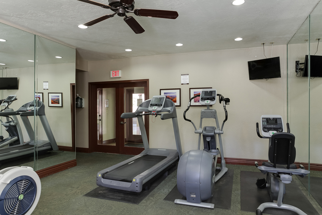 Inviting fitness center with modern exercise equipment, mirrored walls, and a ceiling fan for comfort.