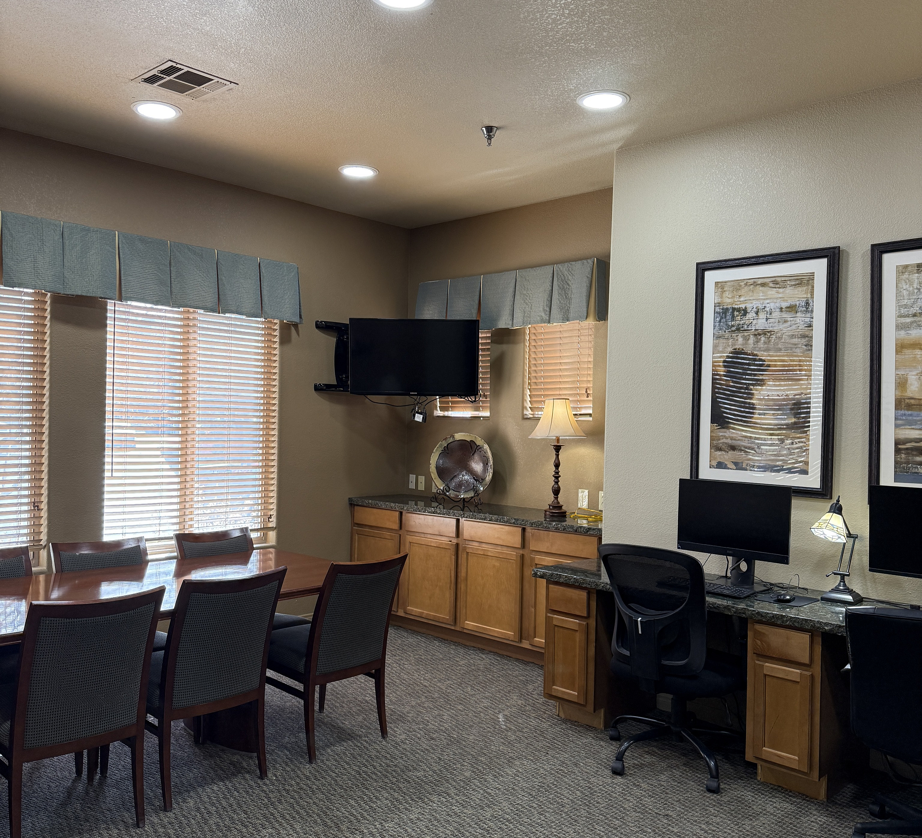 Elegant office space featuring stylish wooden desks, comfortable chairs, modern computers, and warm lighting accents.