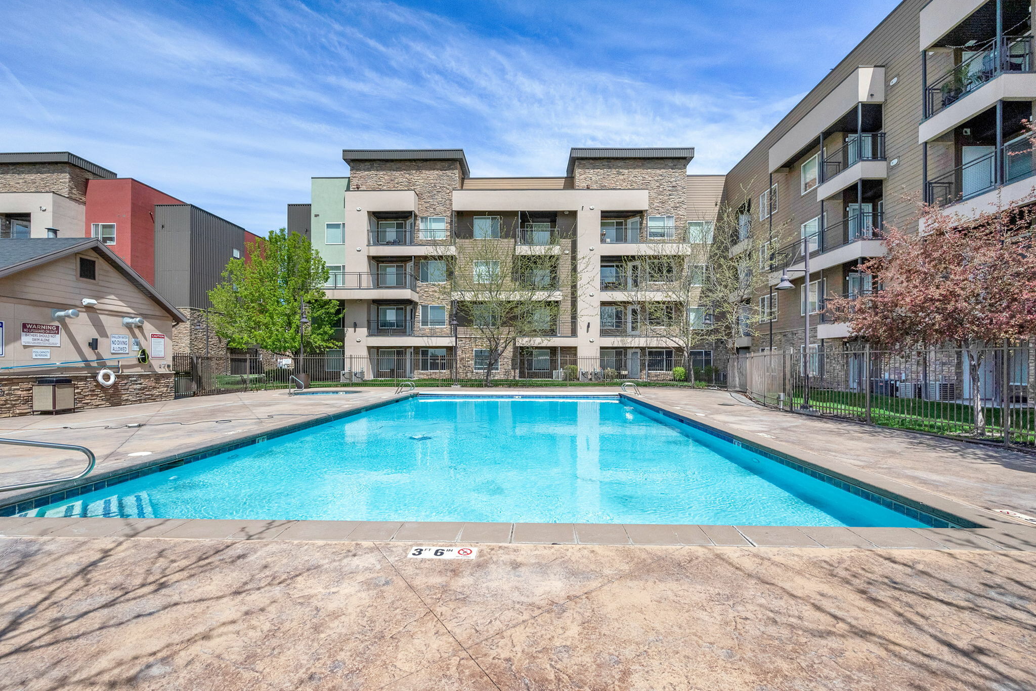 Inviting apartment complex with modern architecture featuring a pristine swimming pool and lush landscaping.
