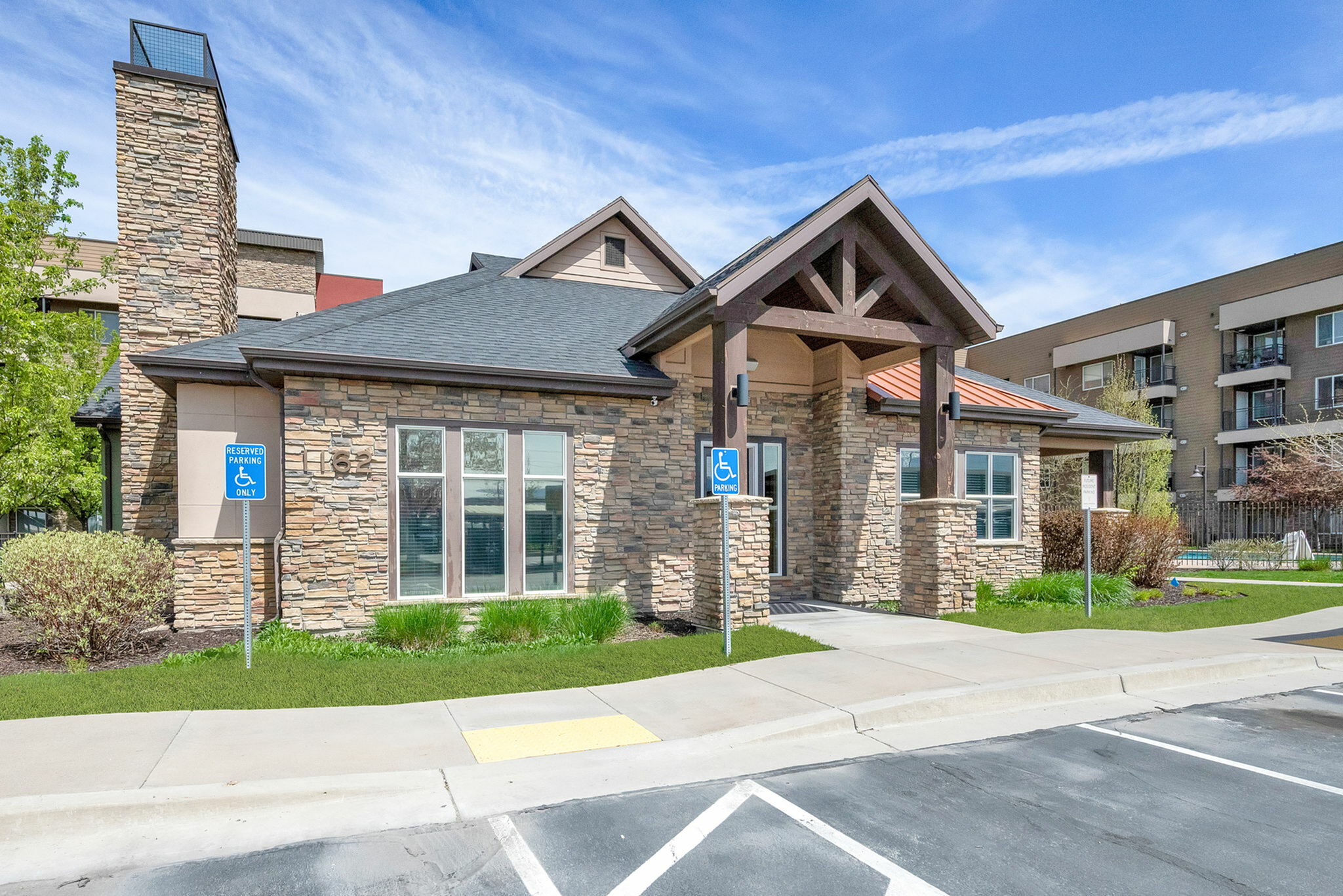 Charming stone-clad building with modern architectural design and accessible parking in a vibrant residential community.