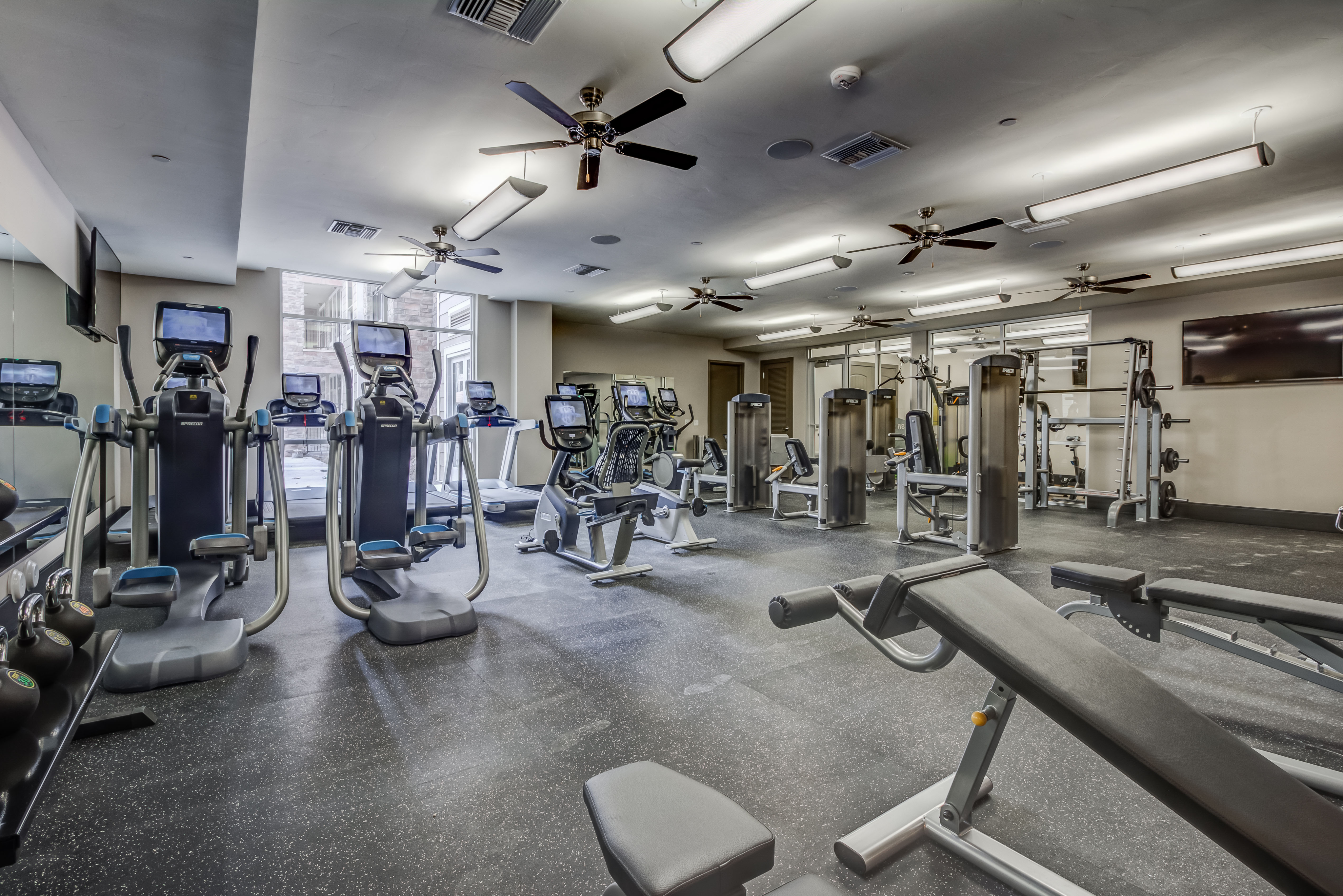 Modern apartment fitness center with top-of-the-line cardio machines, strength training equipment, and ample space for a comprehensive workout.