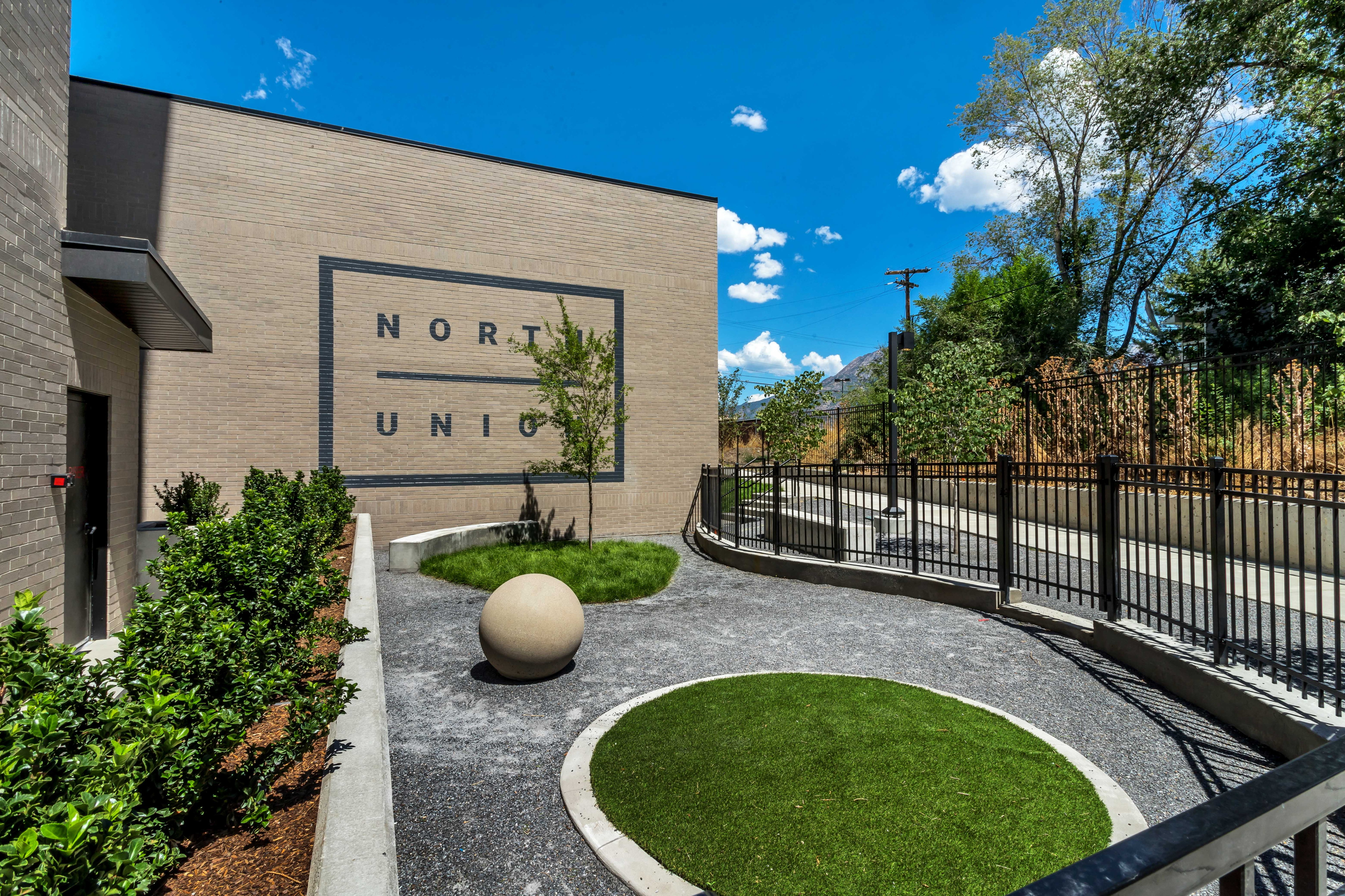 Charming outdoor space at North Union with manicured landscaping, modern architecture, and a bright, clear sky.