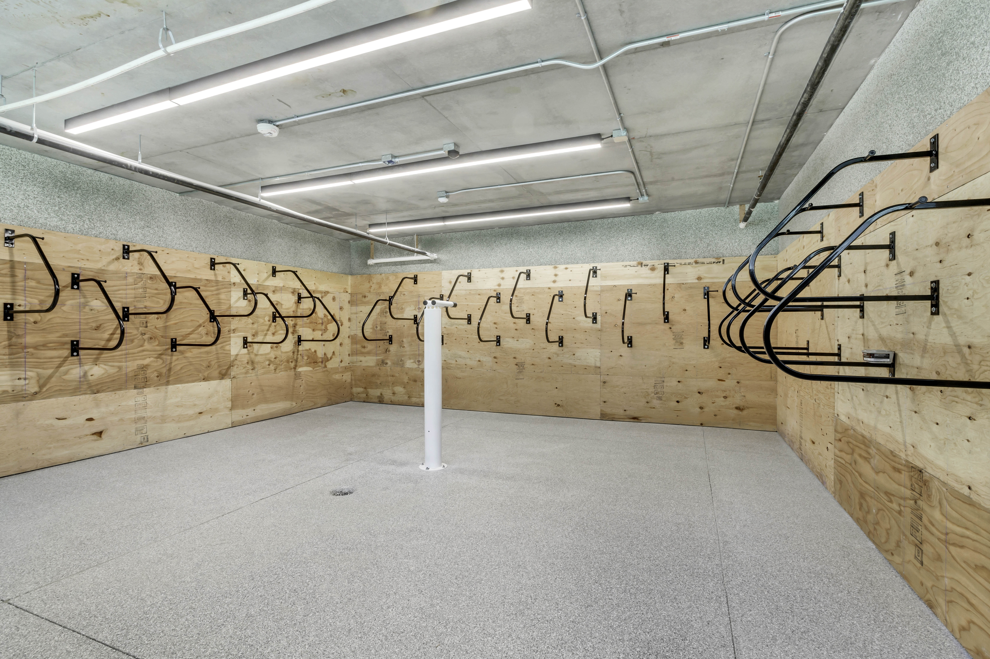 Modern indoor bike storage room with wall-mounted racks and ample space, featuring a sleek industrial design.