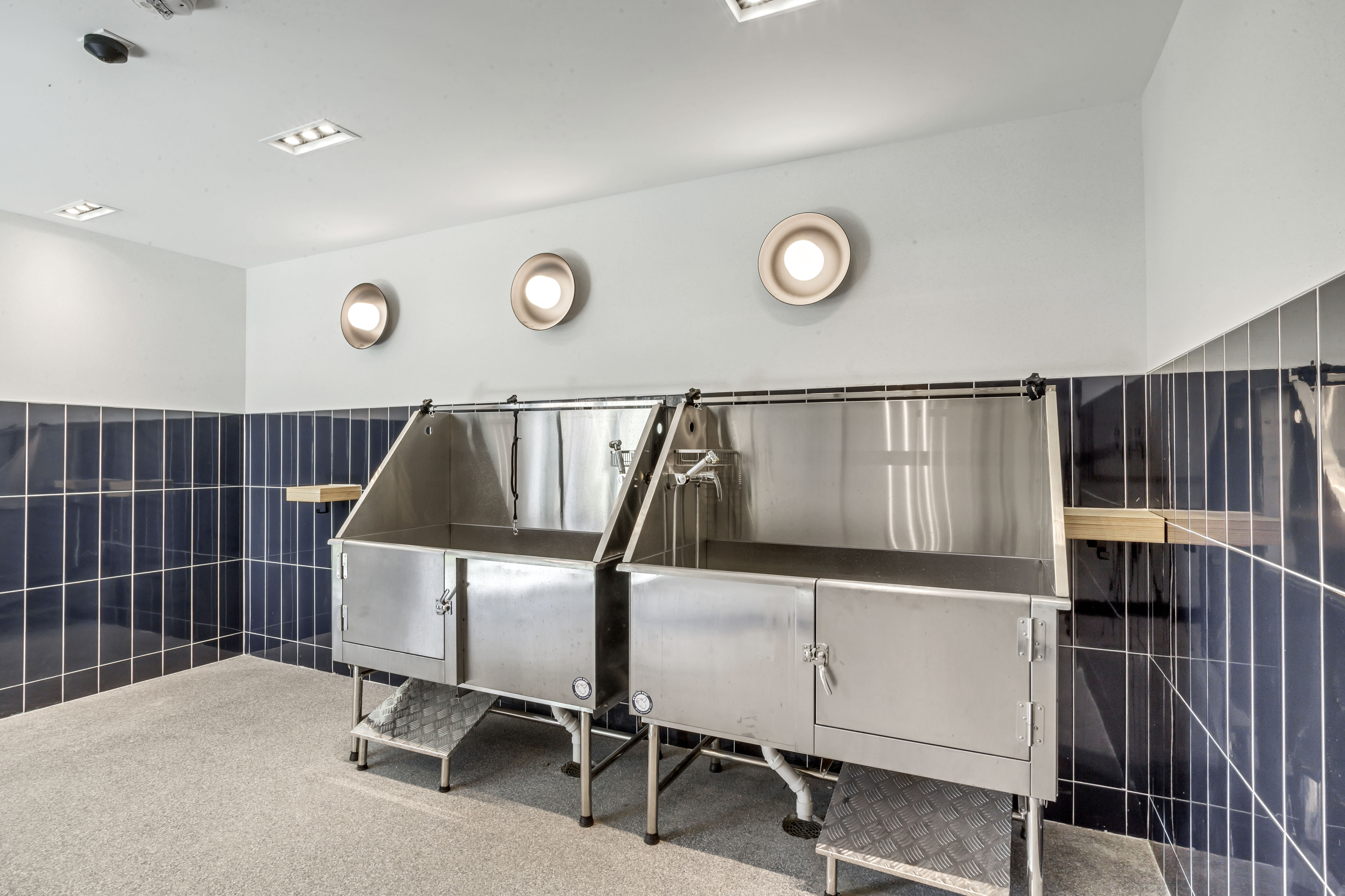 Modern utility room with sleek stainless steel sinks and stylish navy blue tile accents, perfect for functional living.