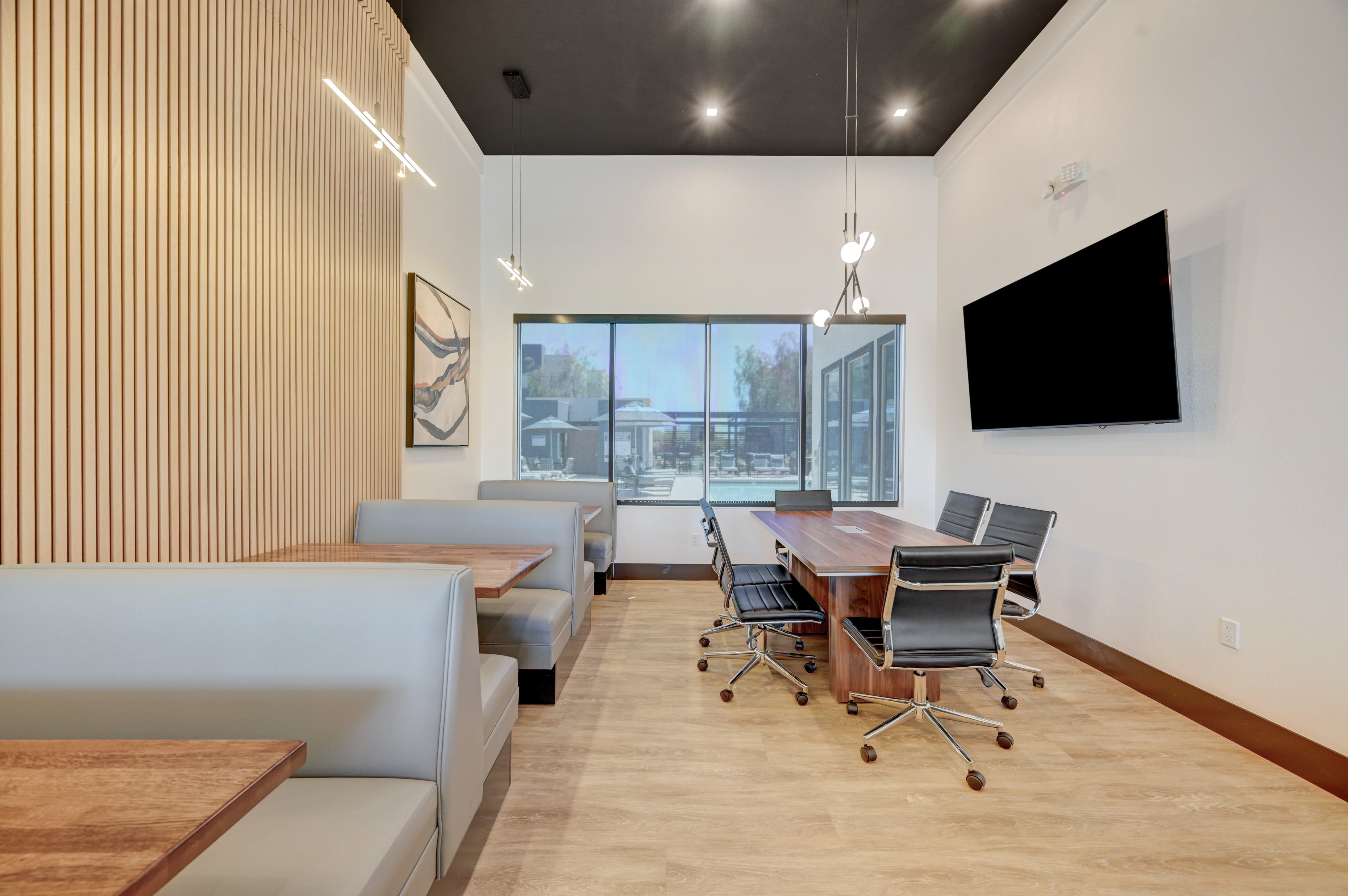 Modern dining and meeting area with sleek furniture, elegant wood paneling, and abundant natural light.